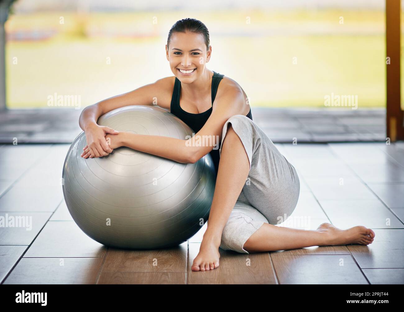 Sentirsi rinfrescati dopo un allenamento. Ritratto completo di una giovane donna seduta contro la palla da ginnastica. Foto Stock