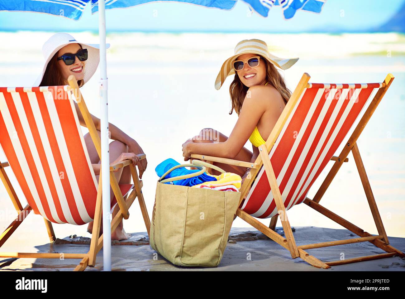 Regalarti i loro migliori sorrisi estivi. Ritratto di due belle giovani donne che mangiano un gelato in spiaggia. Foto Stock