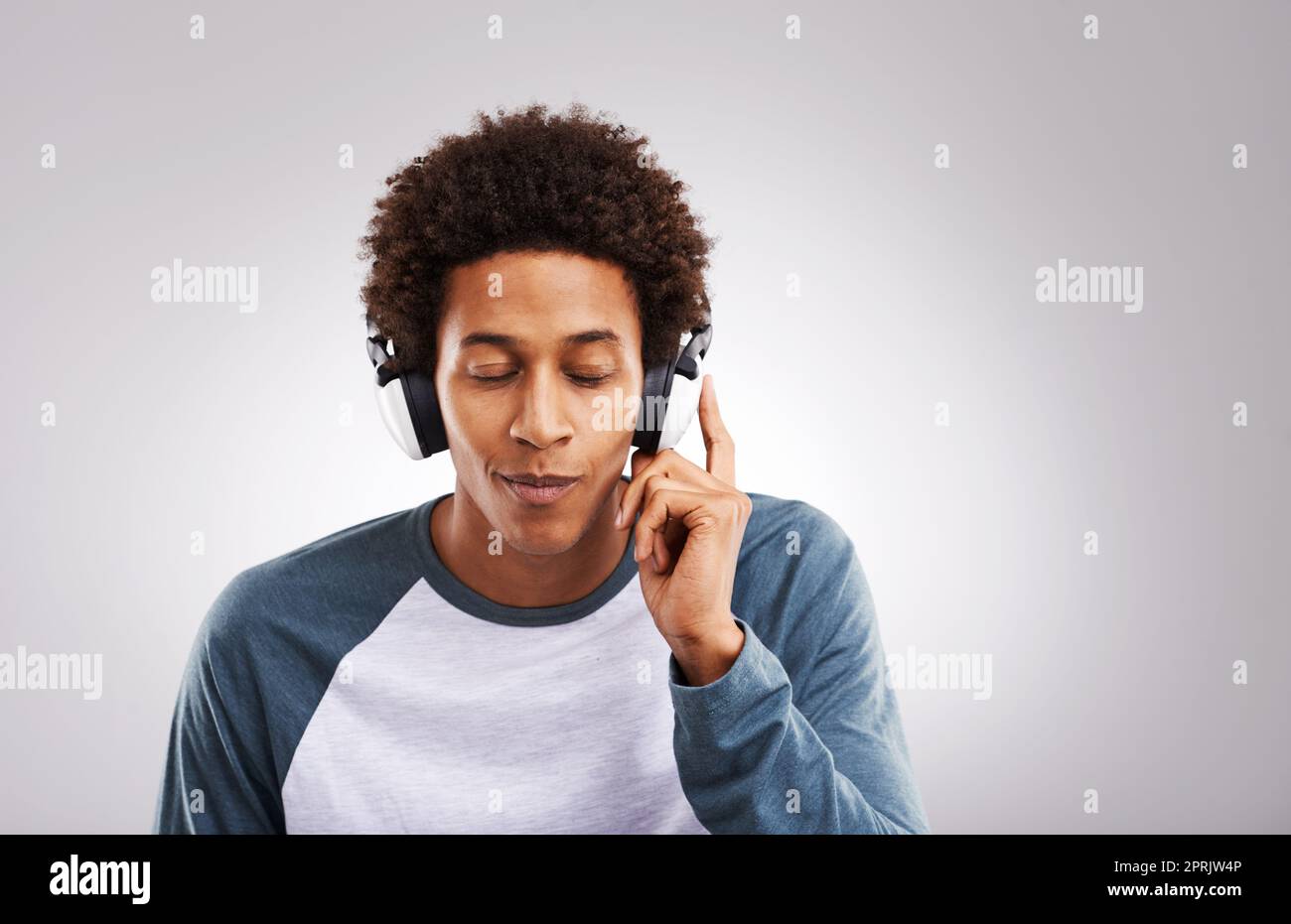 Chiudete gli occhi e lasciate che la musica vi liberi. Studio di un giovane uomo che ascolta musica sulle sue cuffie su uno sfondo grigio. Foto Stock