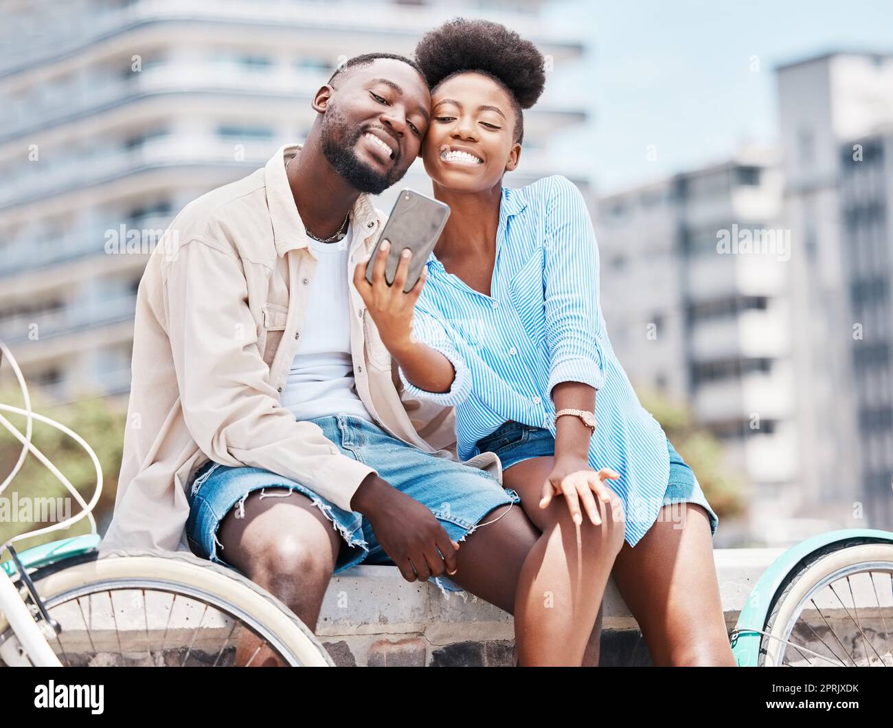 Viaggi in città, bicicletta e selfie in coppia con lo smartphone per un appuntamento, una vacanza o una vacanza estiva. Ritratti felici, uomo e donna o neri, sorridono in foto per contenuti sui social media o ricordi di vlogging Foto Stock