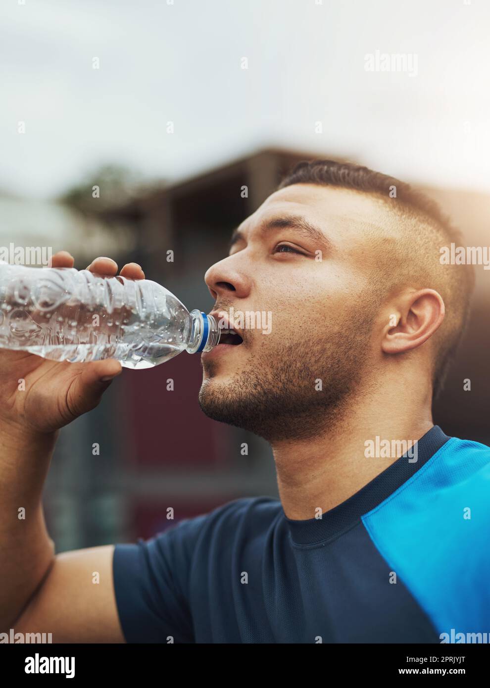 È importante rimanere idratato. Un giovane bevendo dalla sua bottiglia d'acqua mentre fuori per una corsa. Foto Stock