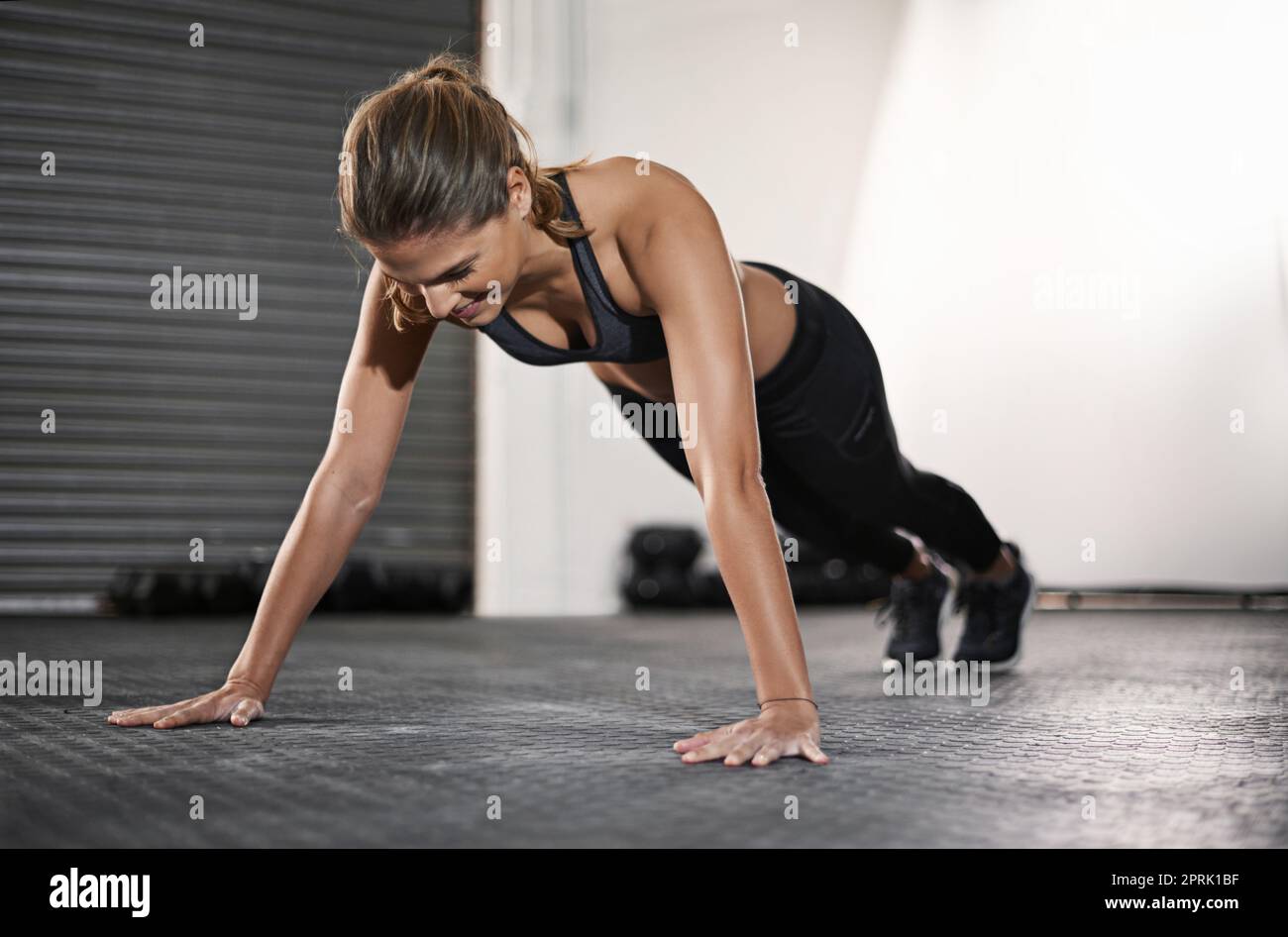 Oggi fa male, domani funziona. Una giovane donna che fa i push-up in palestra. Foto Stock