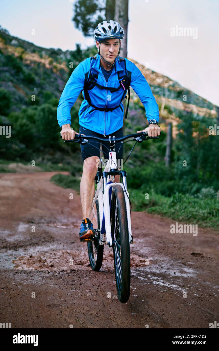 Un ciclista maschile che corre lungo un sentiero per mountain bike. Foto Stock