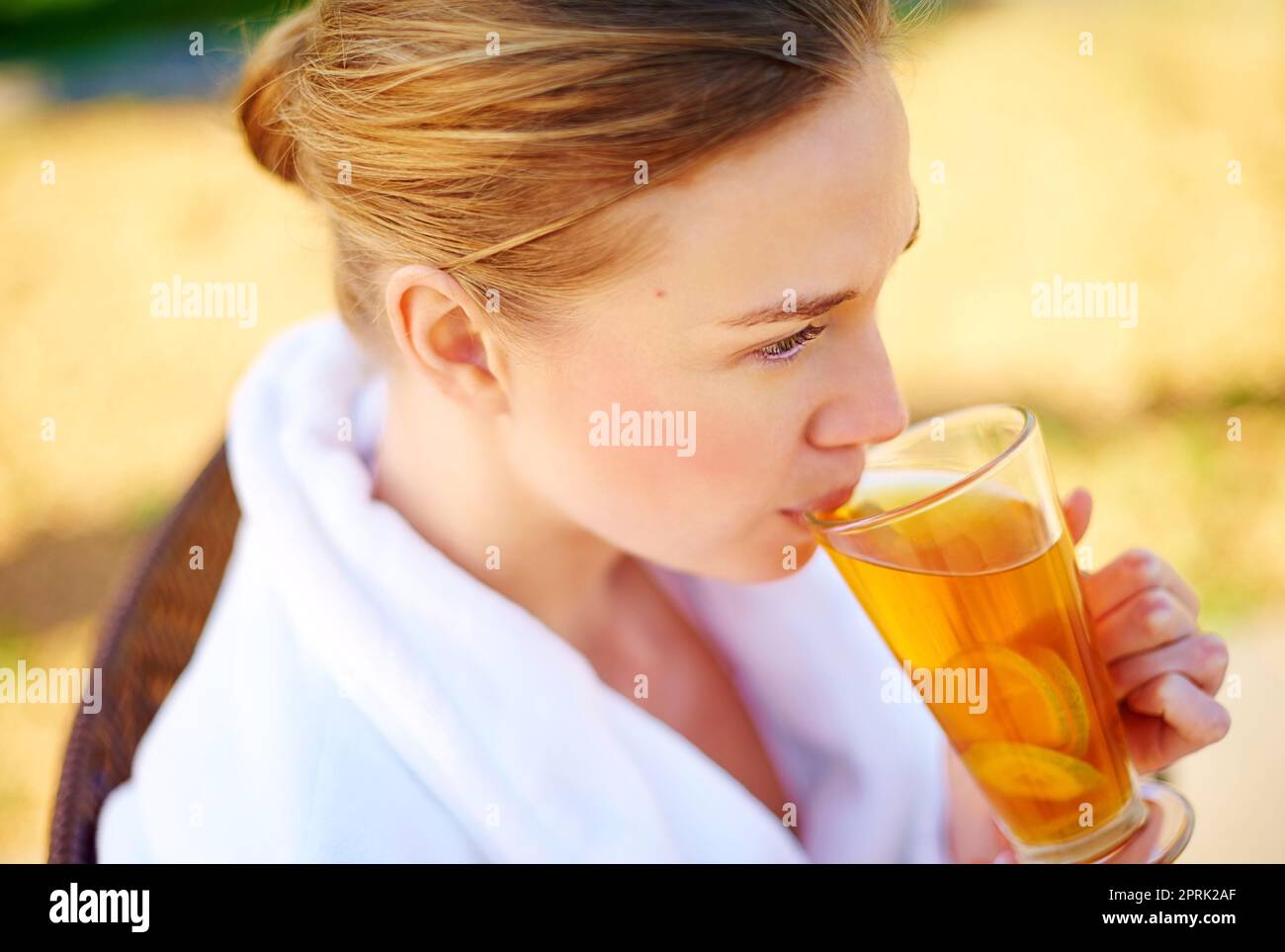 Un sorso della buona vita, una giovane donna che beve un drink in un centro termale. Foto Stock