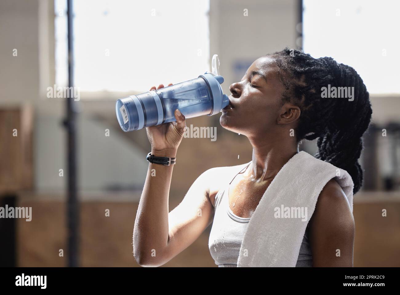 Bere acqua e rilassarsi dopo una sessione di fitness, allenamento e allenamento di una donna atleta. Femmina dalla Nigeria con sudore fatto raggiungere obiettivo di sport cardio obiettivo in una palestra di salute, benessere e sport Foto Stock
