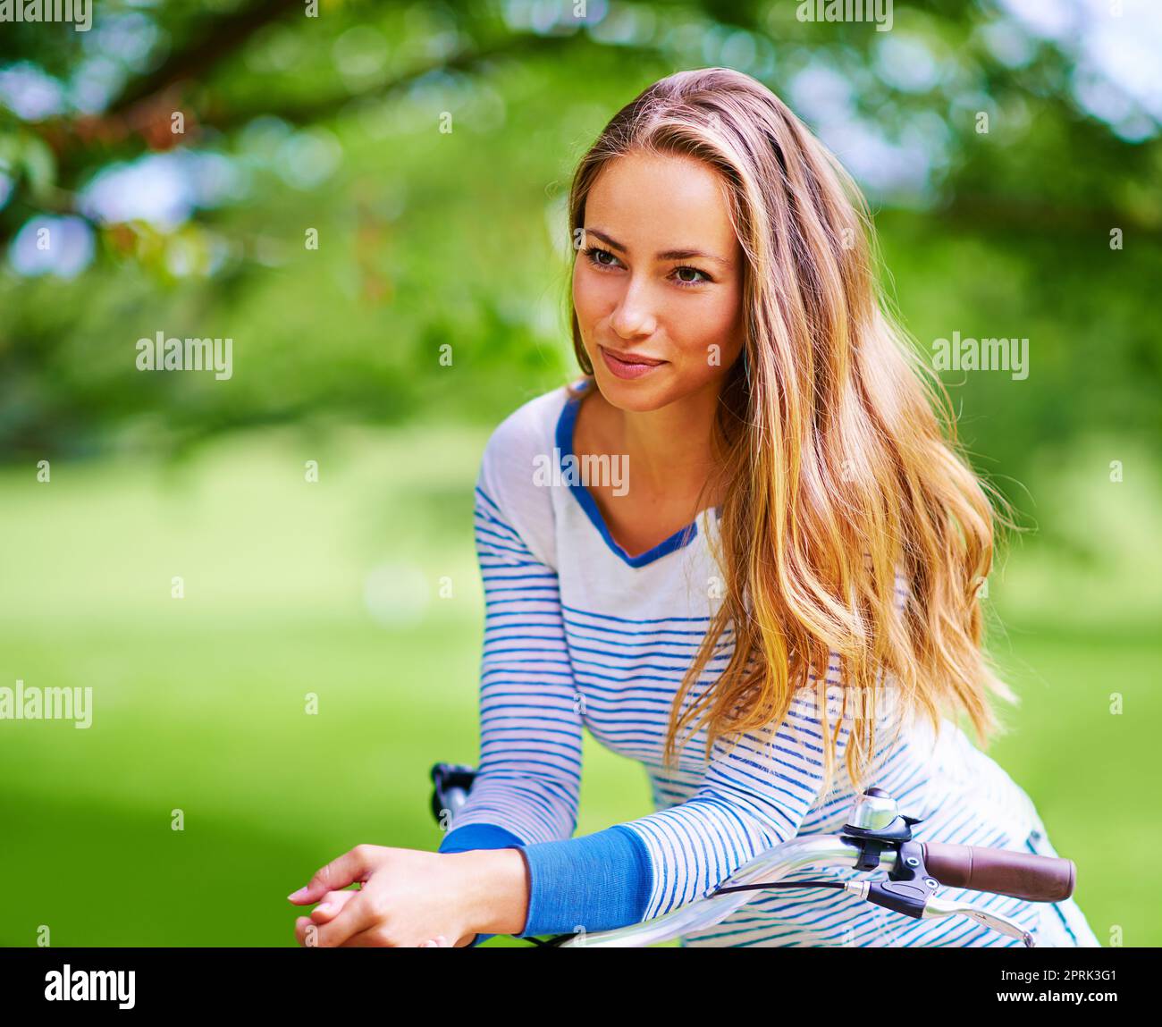 Apprezzare la bellezza della natura, una giovane donna in bicicletta nel parco. Foto Stock