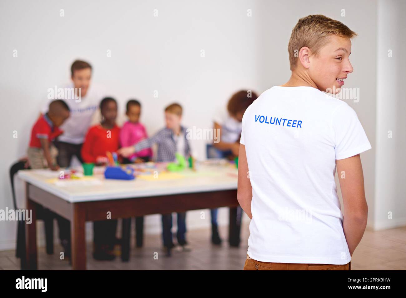 I volontari sono la spina dorsale della comunità. Ripresa da dietro di un volontario che guarda altri volontari che lavorano con bambini piccoli sullo sfondo. Foto Stock