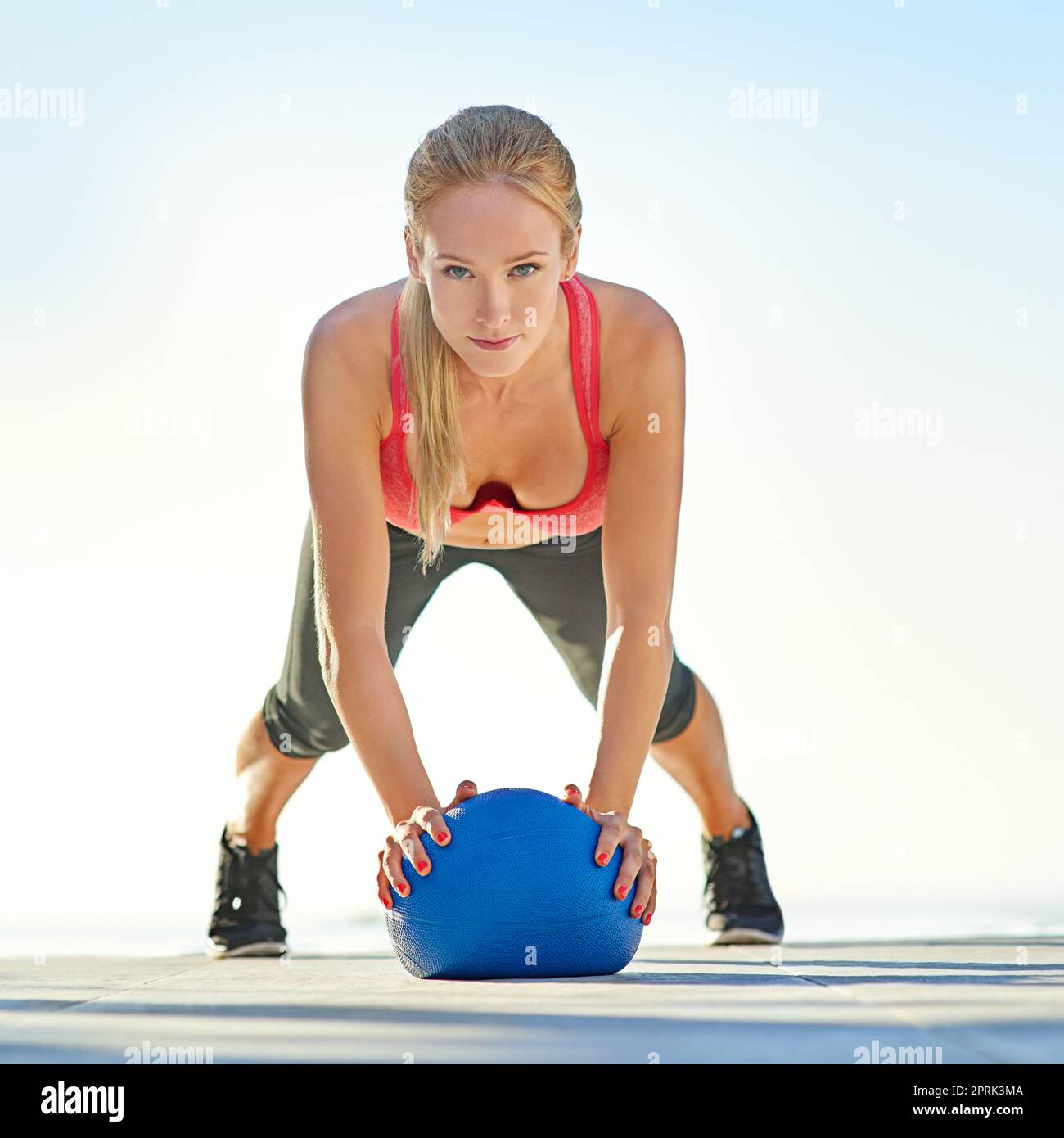Prende sul serio il suo fitness. Ritratto completo di una giovane donna che fa pushup con una palla medica. Foto Stock