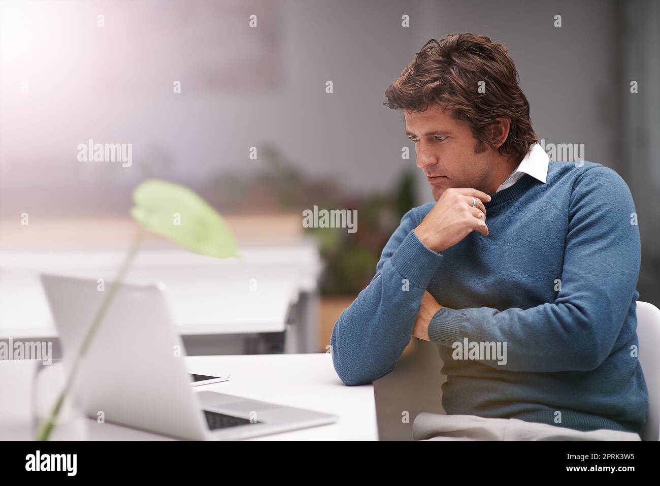 Lavora sodo perché è appassionato della sua professione. Un uomo d'affari che lavora su un computer portatile in ufficio. Foto Stock