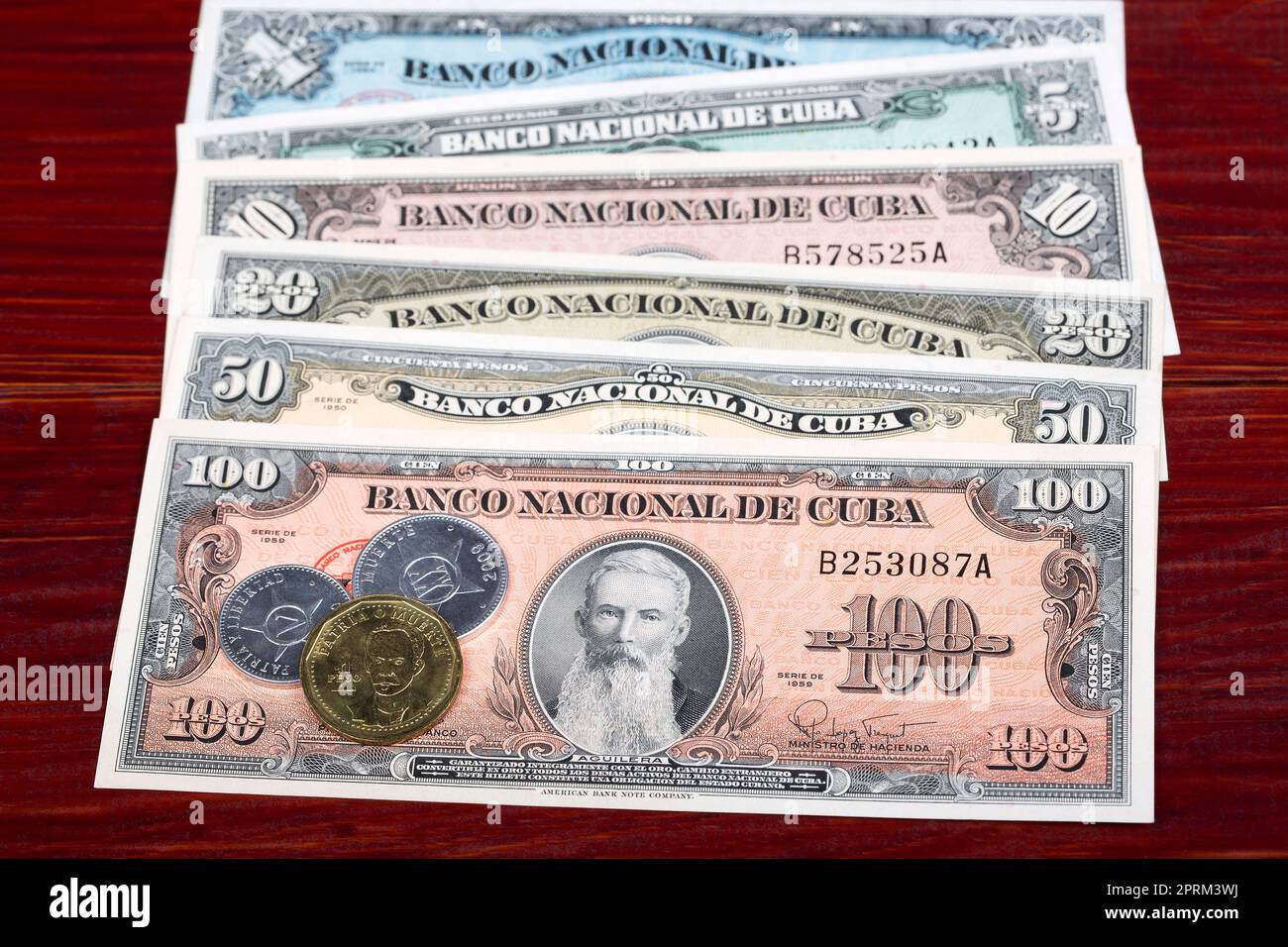 Vecchie monete e banconote cubane pesos su sfondo di legno Foto Stock
