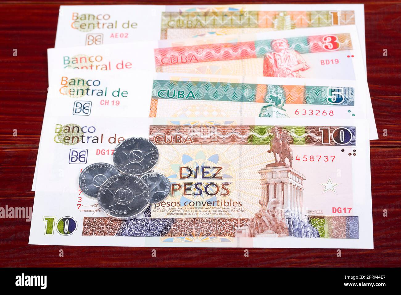 Monete e banconote cubane pesos su sfondo di legno Foto Stock