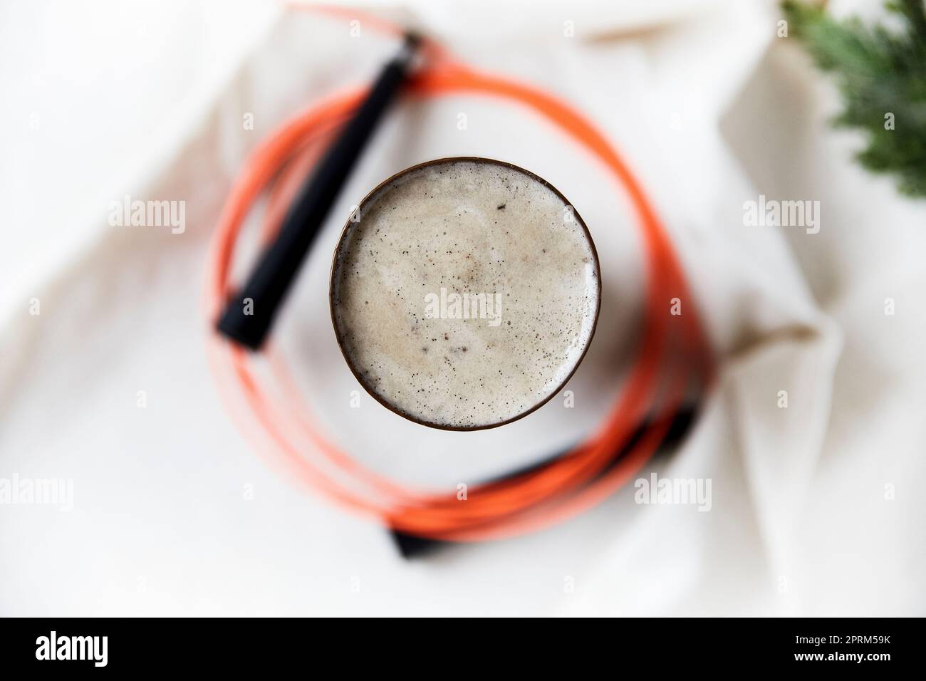 Mangiare sano ed esercitare uno stile di vita sano. Foto dall'alto di un frullato di semi di chia circondato da una corda da salto su un panno da tavolo bianco Foto Stock