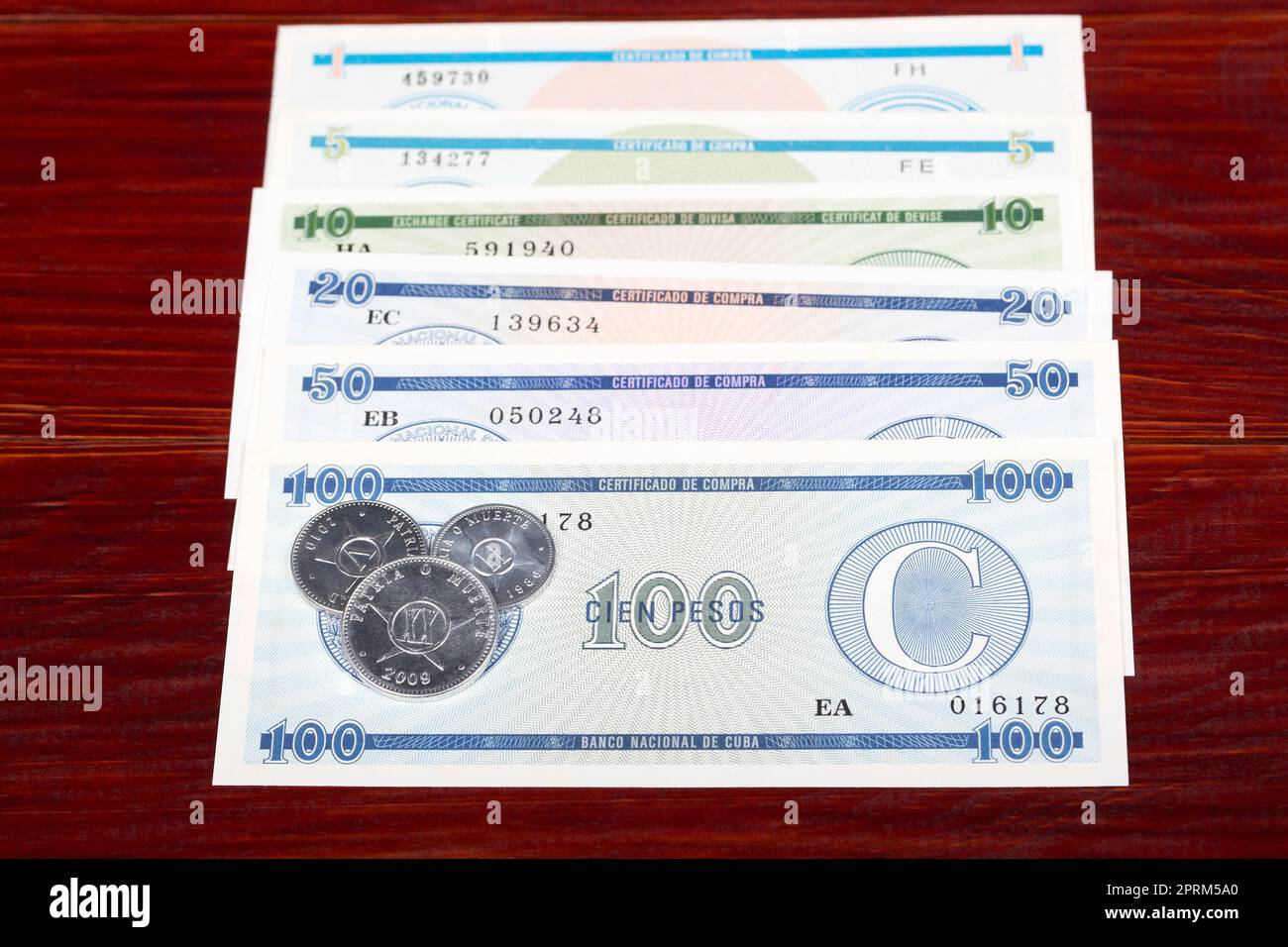 Monete e banconote cubane pesos su sfondo di legno Foto Stock