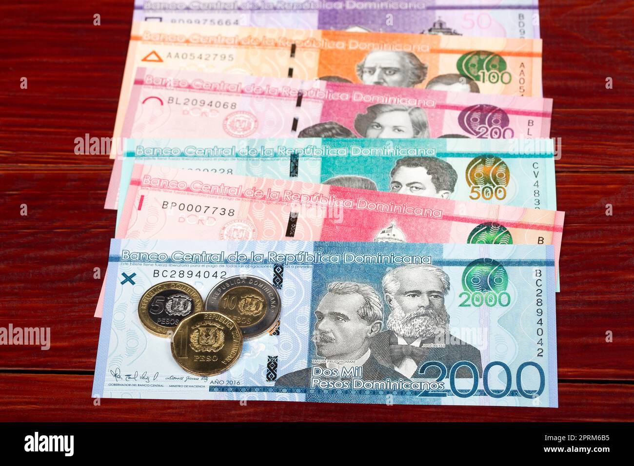 Monete e banconote dominicane pesos su sfondo ligneo Foto Stock