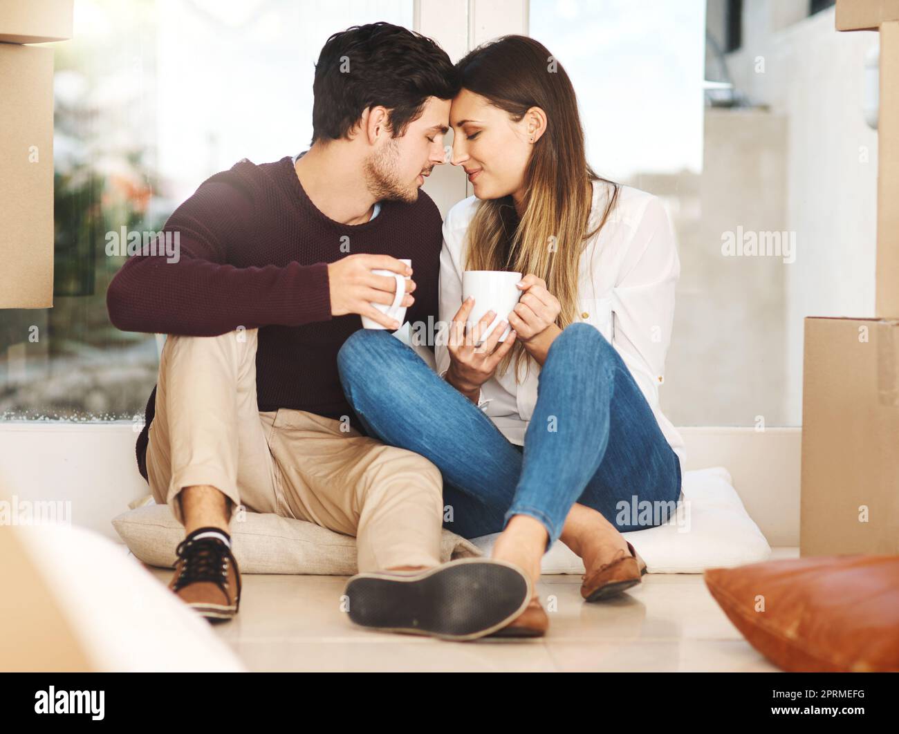 Una giovane coppia affettuosa che prende una pausa caffè mentre si sposta in una nuova casa. Foto Stock
