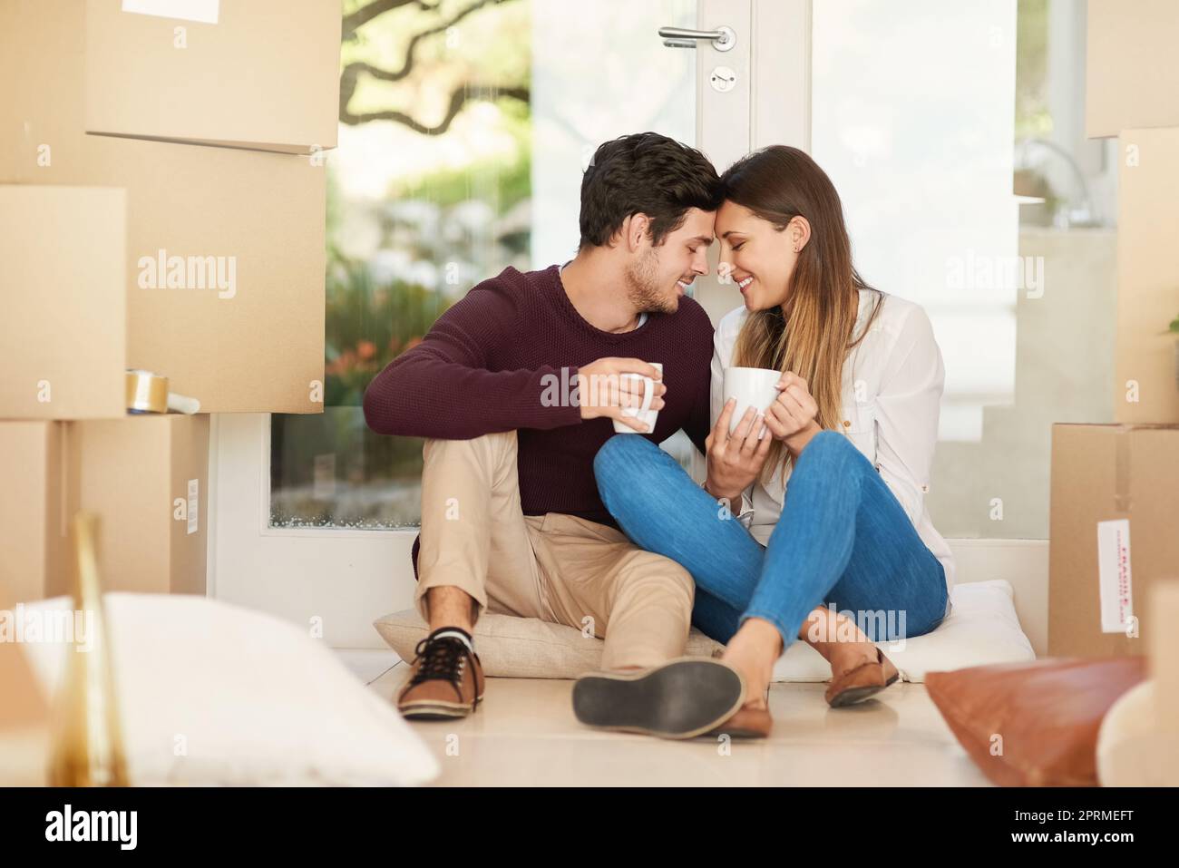 Una giovane coppia affettuosa che prende una pausa caffè mentre si sposta in una nuova casa. Foto Stock