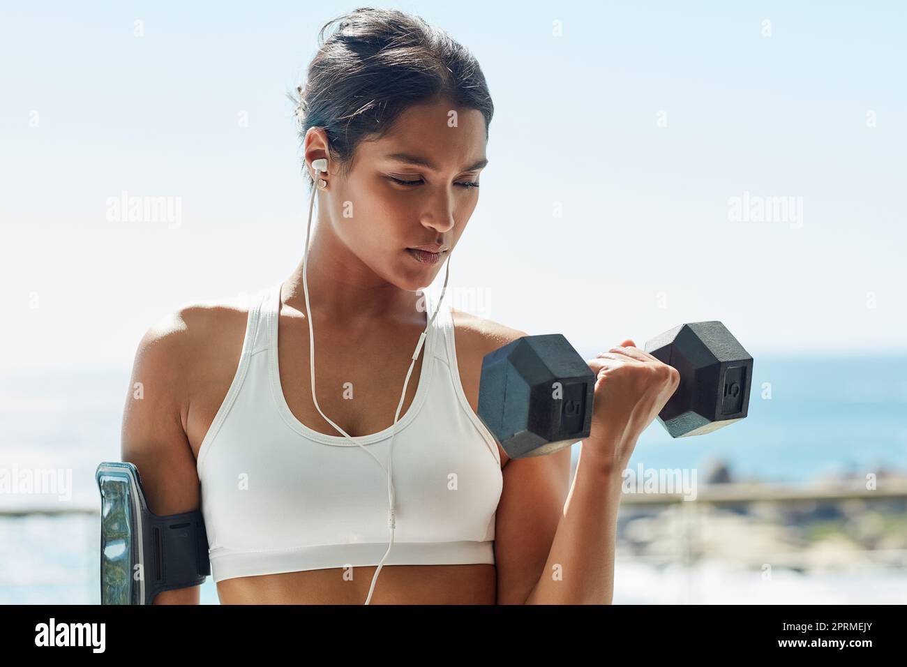 Più forte, più sottile e più sano ogni giorno. Una giovane donna che usa manubri nella sua routine di allenamento. Foto Stock