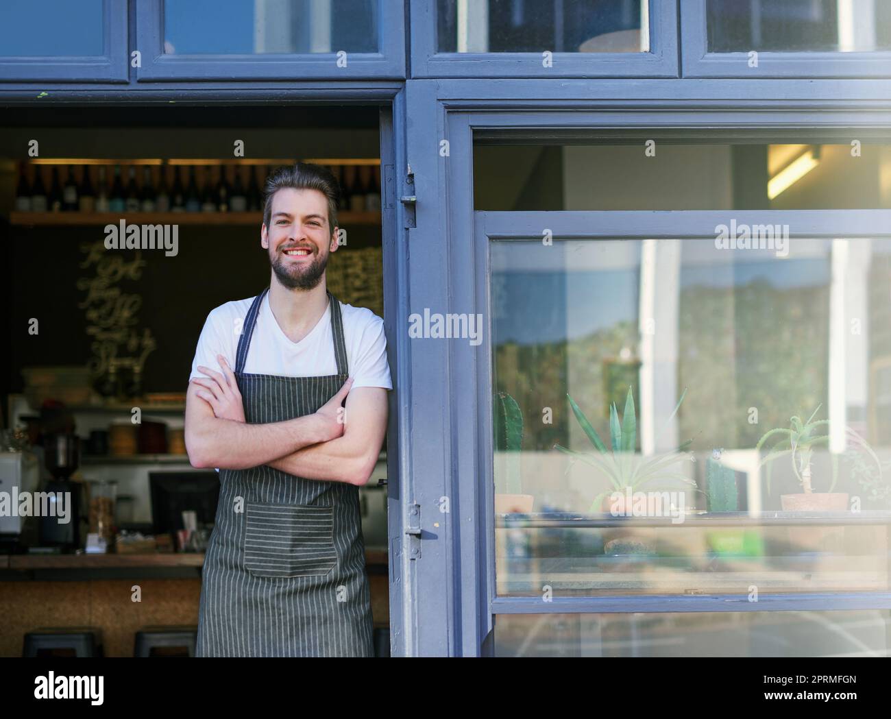 Il mio bar è aperto per affari. Ritratto di un giovane in piedi all'ingresso della sua caffetteria. Foto Stock