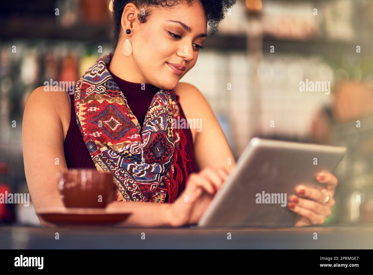 Ces racking up i mi piace sul suo aggiornamento di stato. Una giovane donna attraente utilizzando un tablet digitale in un bar. Foto Stock