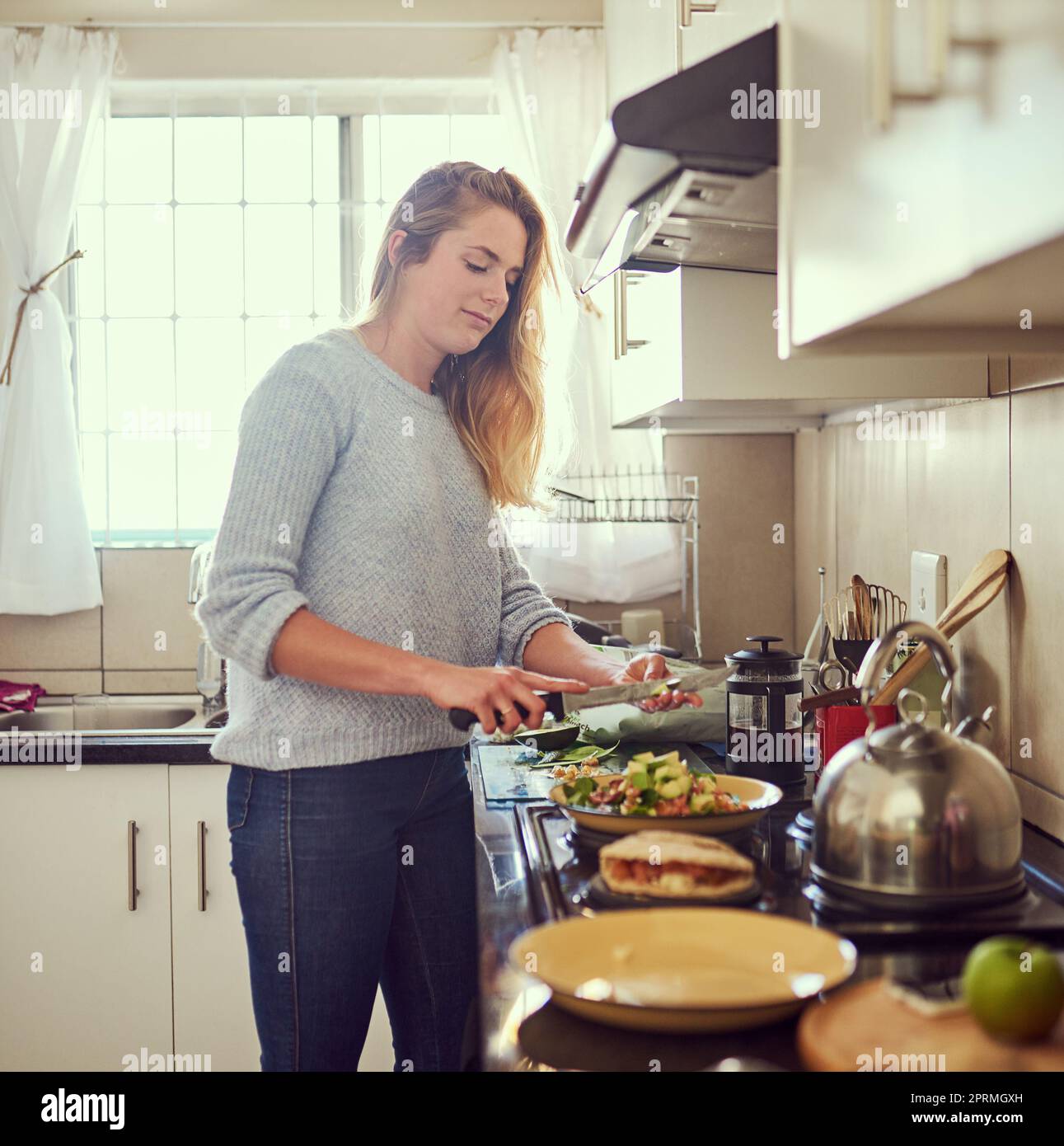 Preparare un pasto sano e ben equilibrato. Una giovane donna attraente preparare un pasto nutriente a casa. Foto Stock