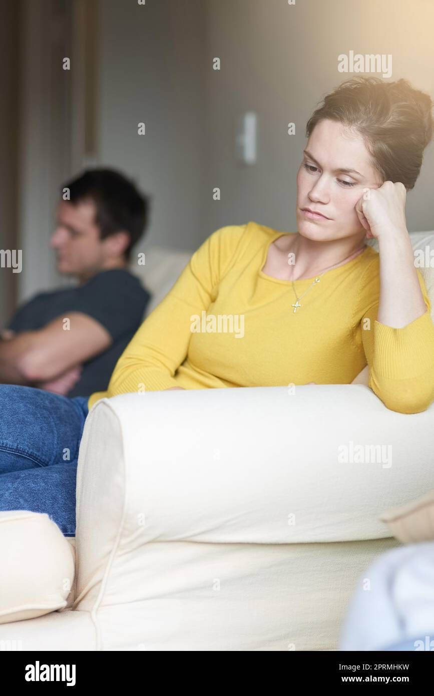 I rapporti hanno i loro alti e bassi. Una giovane coppia infelice seduta sul divano a casa dopo una lotta. Foto Stock
