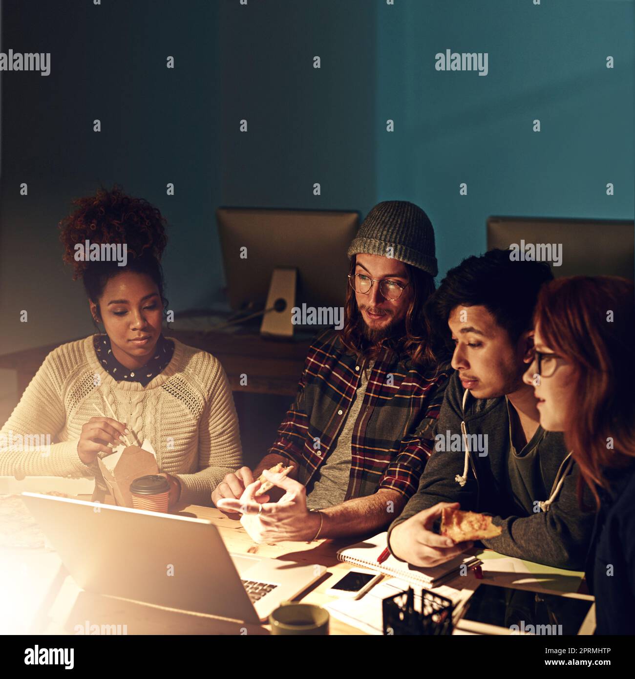 Lavorare insieme per superare la scadenza. Un team aziendale che utilizza un notebook insieme durante un turno di notte al lavoro. Foto Stock