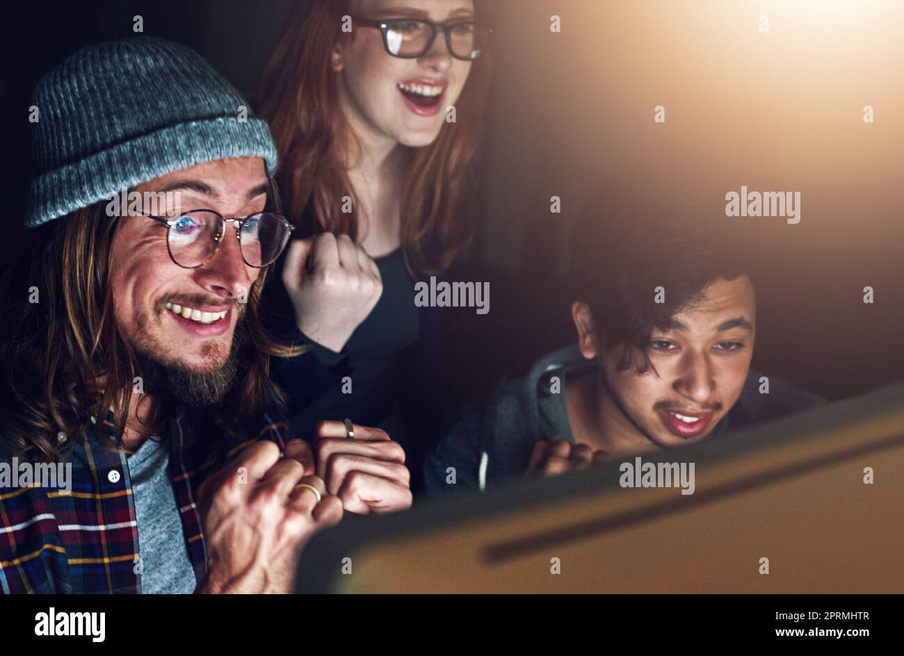 Il lavoro duro paga sempre. Un team di affari che guarda uno schermo del computer insieme durante un turno di notte al lavoro. Foto Stock