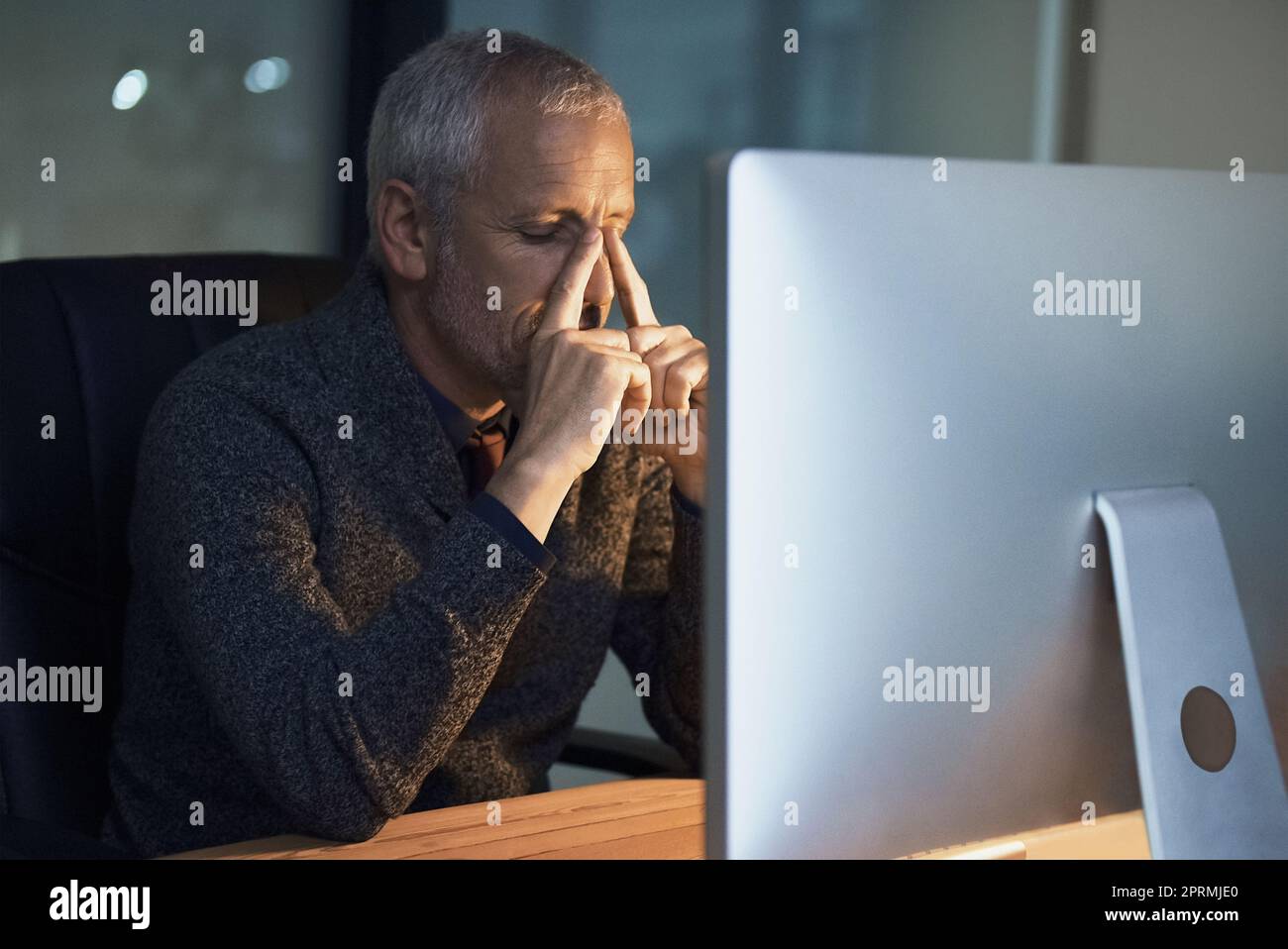 Cercando di mantenere la calma sotto pressione. Un uomo d'affari maturo che guarda stressato mentre lavora tardi in ufficio. Foto Stock