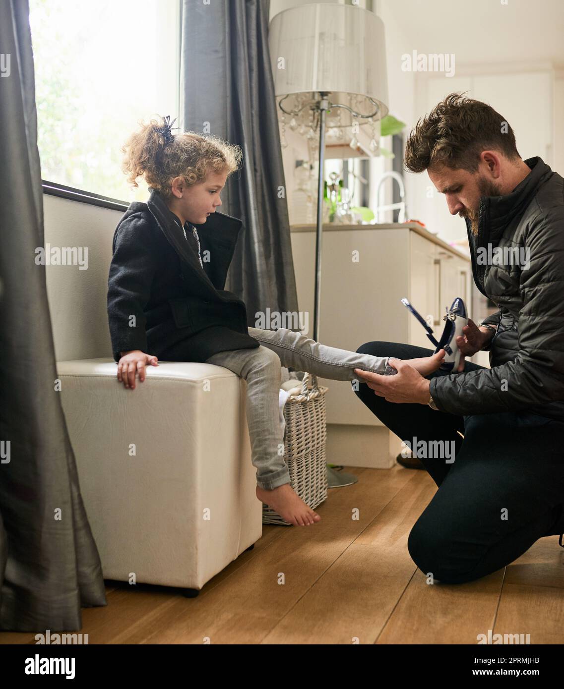 Papà sarà sempre lì per aiutarla, un padre che aiuta sua figlia a indossare le scarpe a casa. Foto Stock