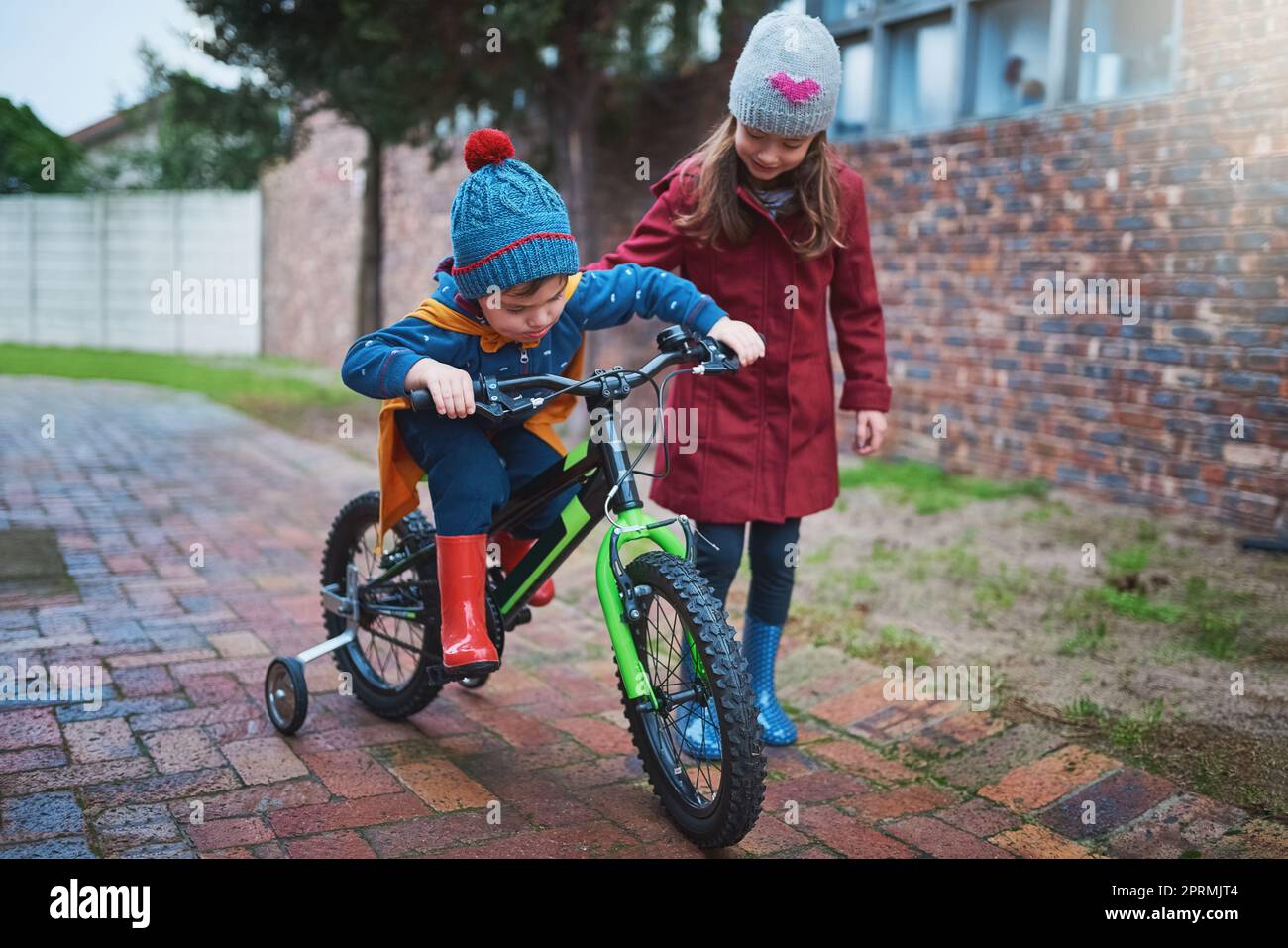 Grande sis sarà sempre lì per aiutarlo. Una bambina che insegna a suo fratello come andare in bicicletta fuori. Foto Stock