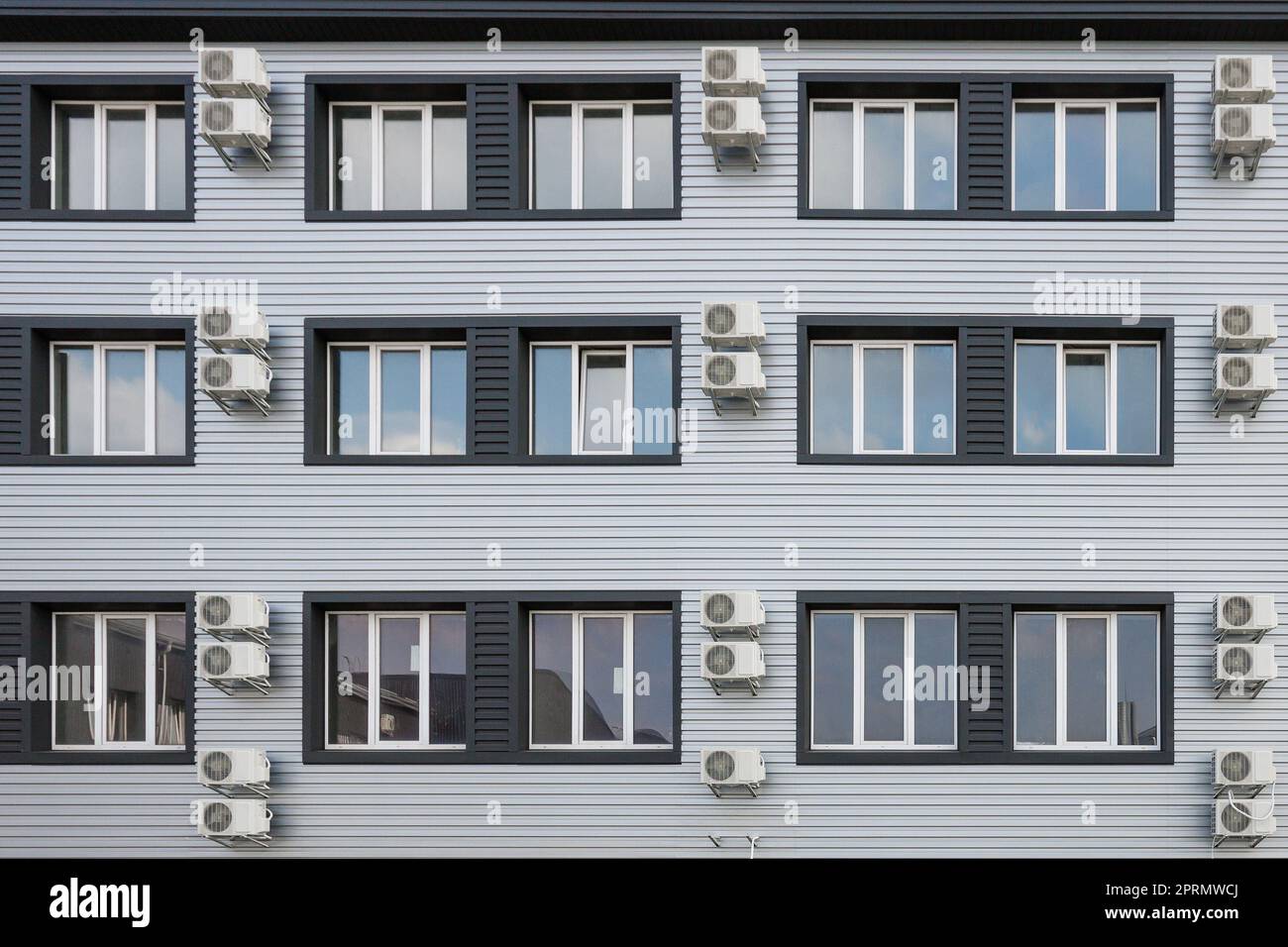 Molti condizionatori d'aria sono appesi alla facciata di un nuovo edificio moderno. Foto Stock