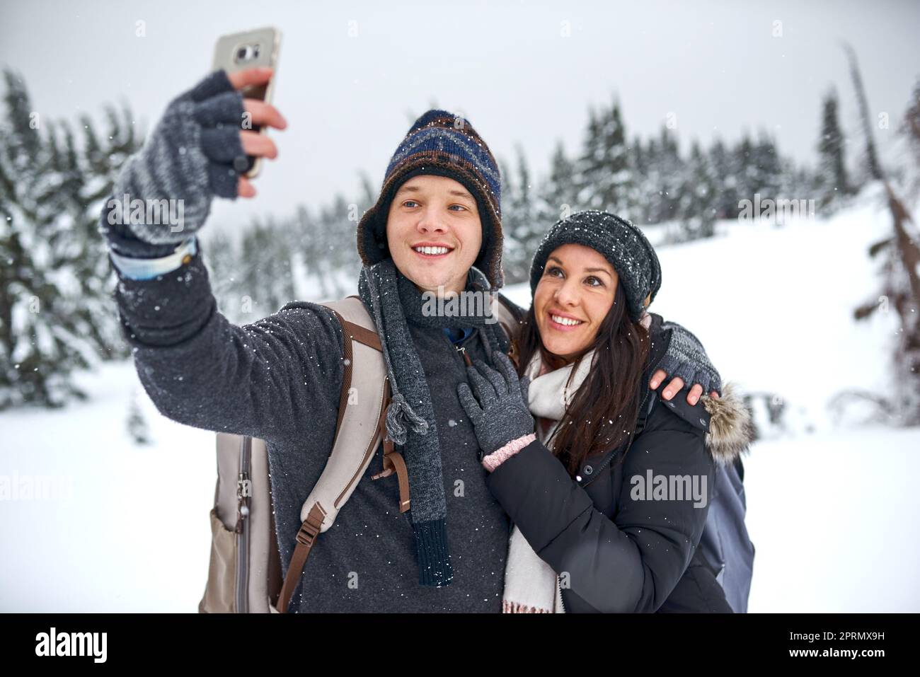 Ci piace scattare selfie. un uomo che prende un selfie con la sua ragazza mentre fuori sulla neve Foto Stock