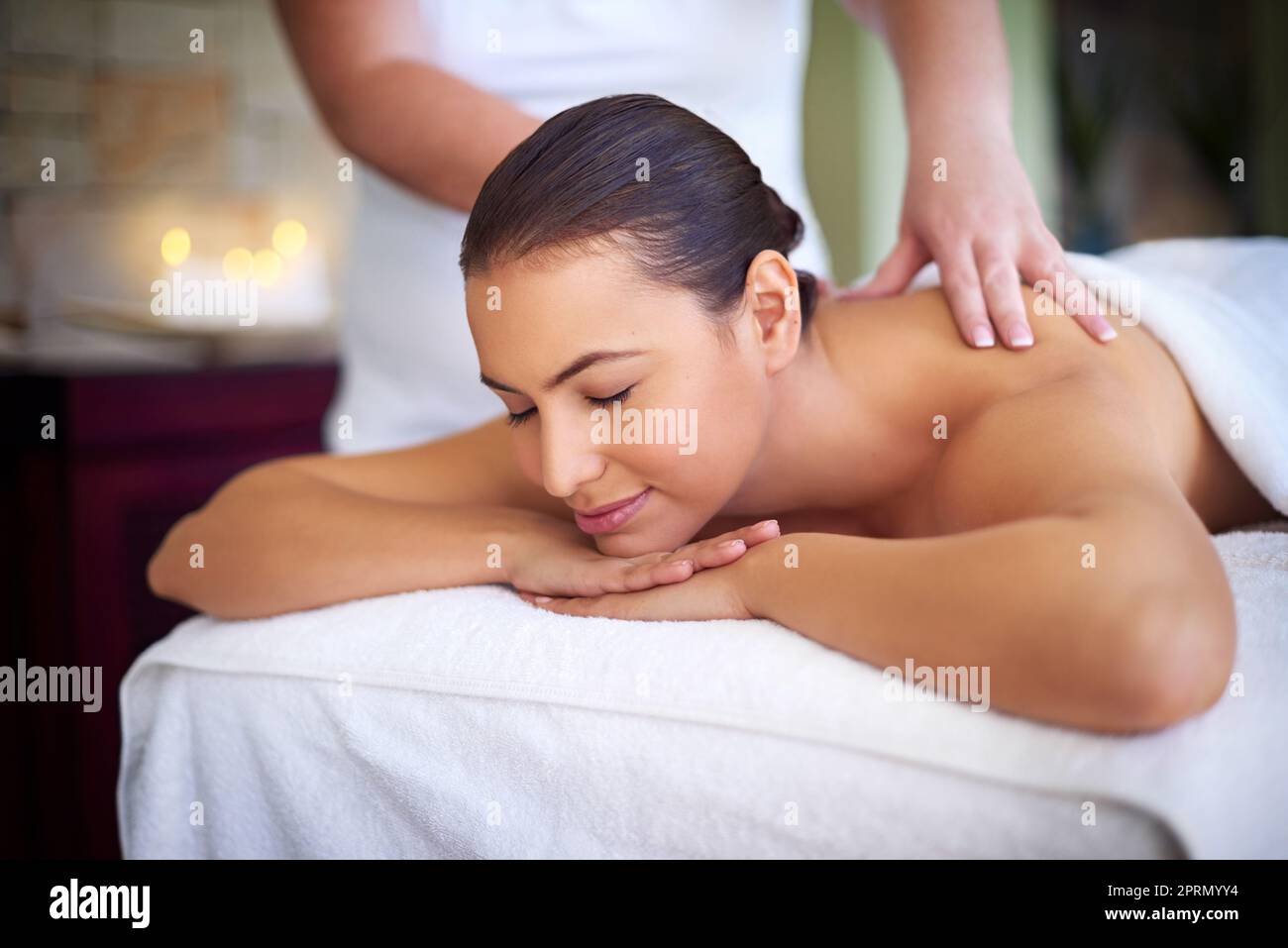 Cedendo alla serenità, una giovane donna che si diverse con un massaggio alla schiena in una spa. Foto Stock