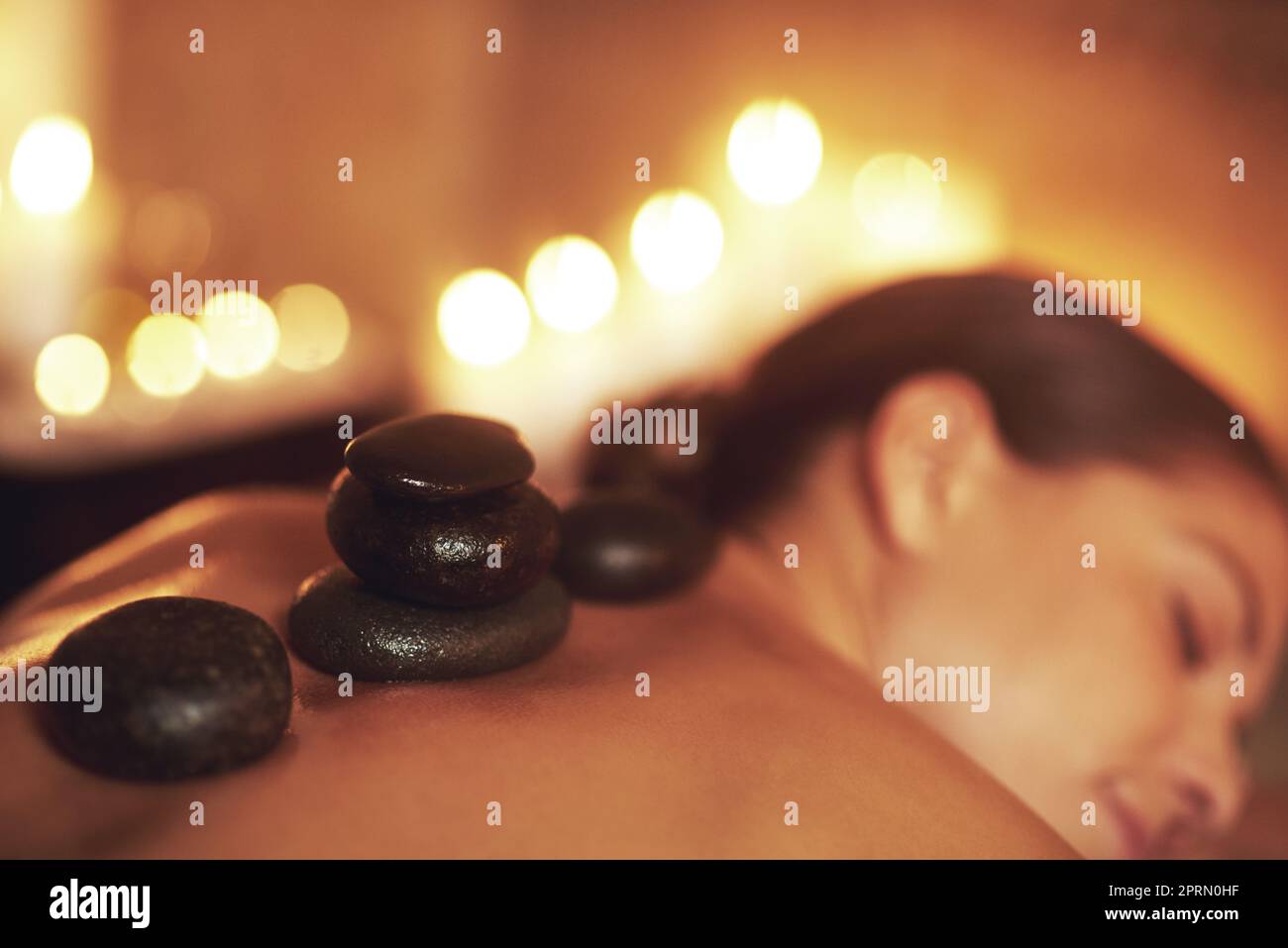Questo massaggio sfavilla. Una giovane donna che gode un massaggio di pietra calda. Foto Stock