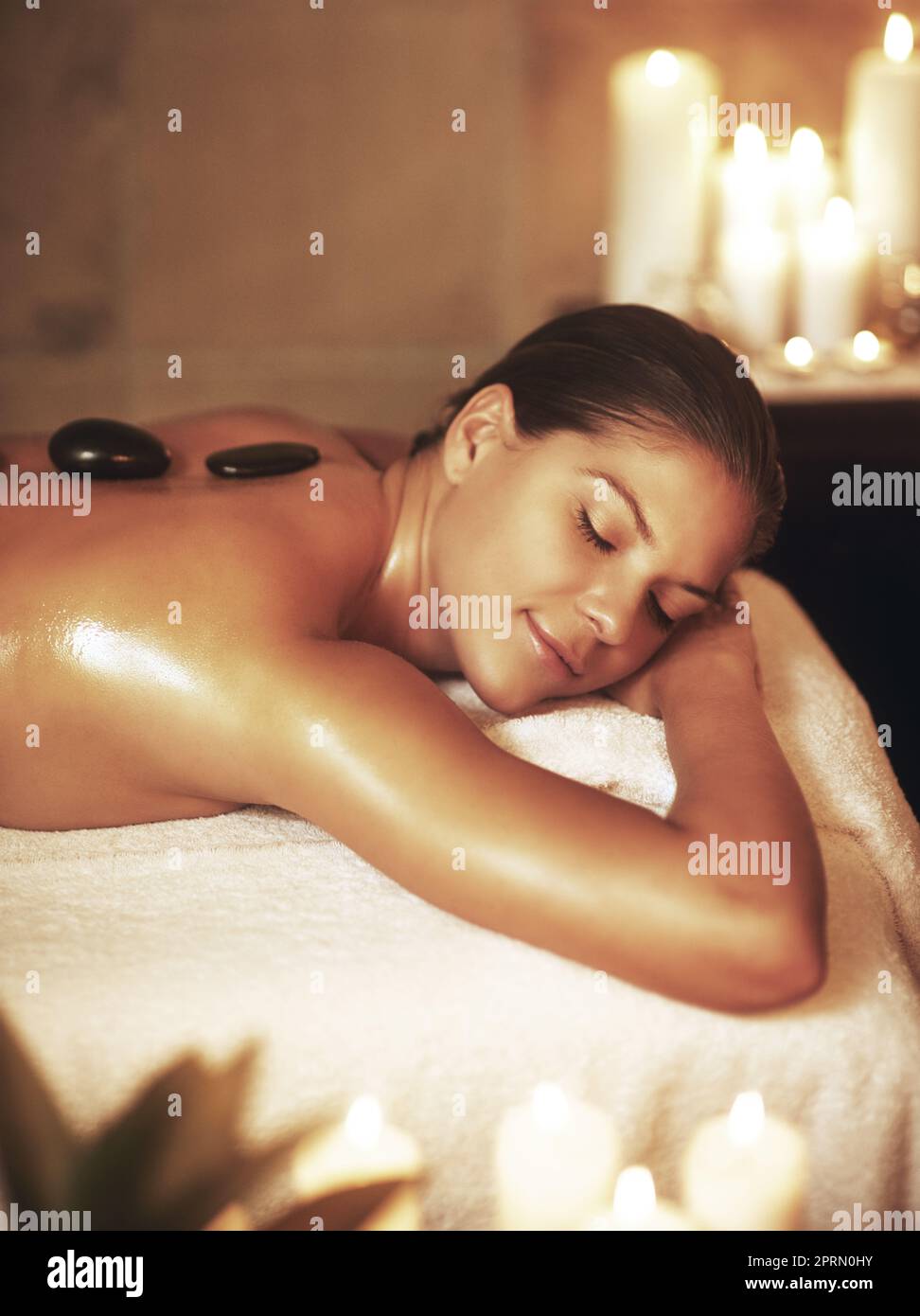 Mi merita di essere coccolata: Una giovane donna che si diverte con un massaggio con pietre calde. Foto Stock
