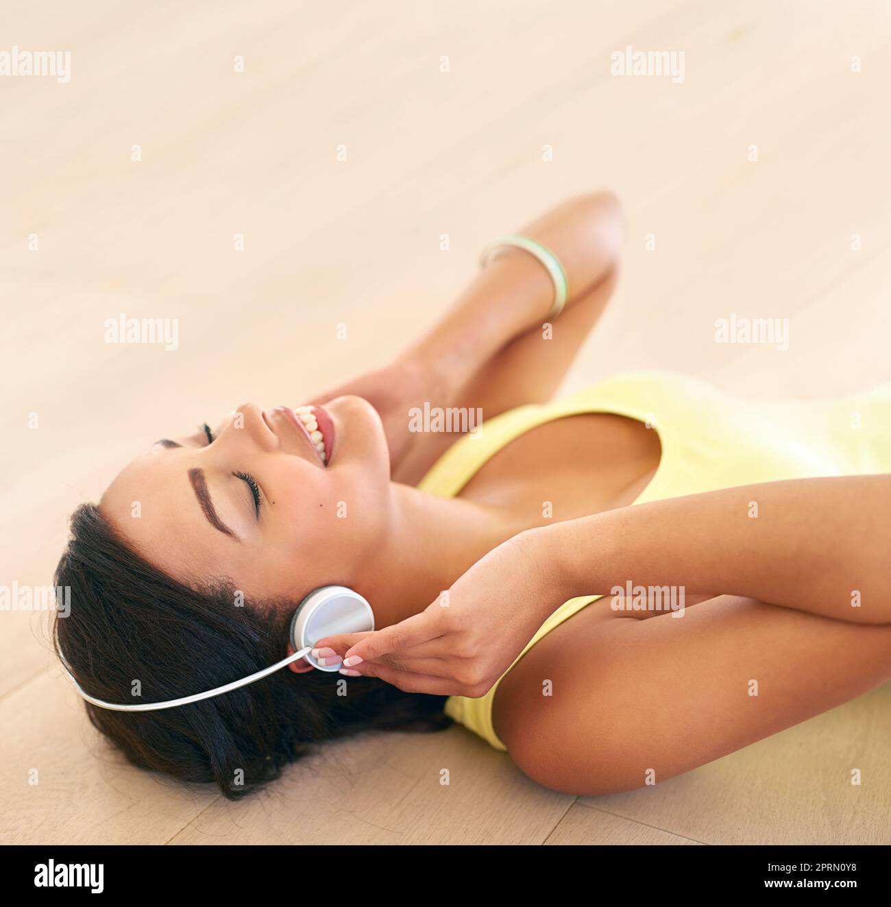 Perdersi nella musica, una giovane donna che ascolta la musica sdraiata su un pavimento di legno. Foto Stock