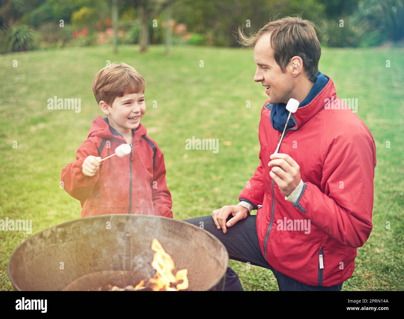 La migliore delizia dolce di sempre. Un padre e un figlio arrostire marshmallows sopra un fuoco. Foto Stock