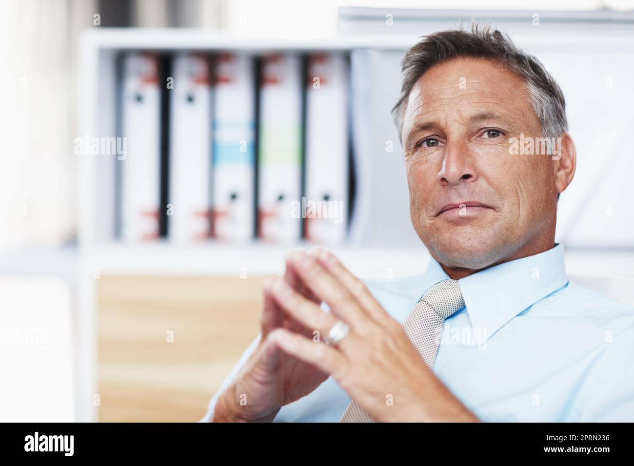 Contemplare la vostra proposta commerciale. Ritratto di un manager aziendale rispettato seduto alla sua scrivania con mani rude. Foto Stock