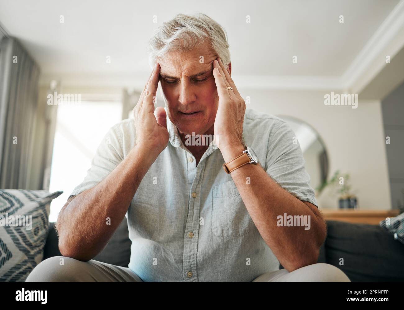 Uomo anziano con mal di testa, stress o ansia per la pensione, problemi finanziari o ipoteca casa nel suo salotto. Uomo anziano malato con emicrania p Foto Stock