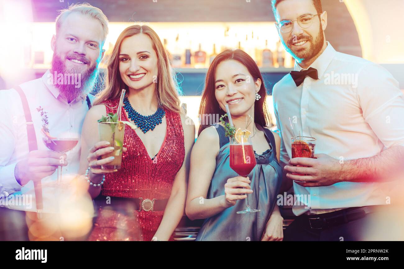 Ritratto di una giovane coppia felice che tiene in mano un drink al night club Foto Stock