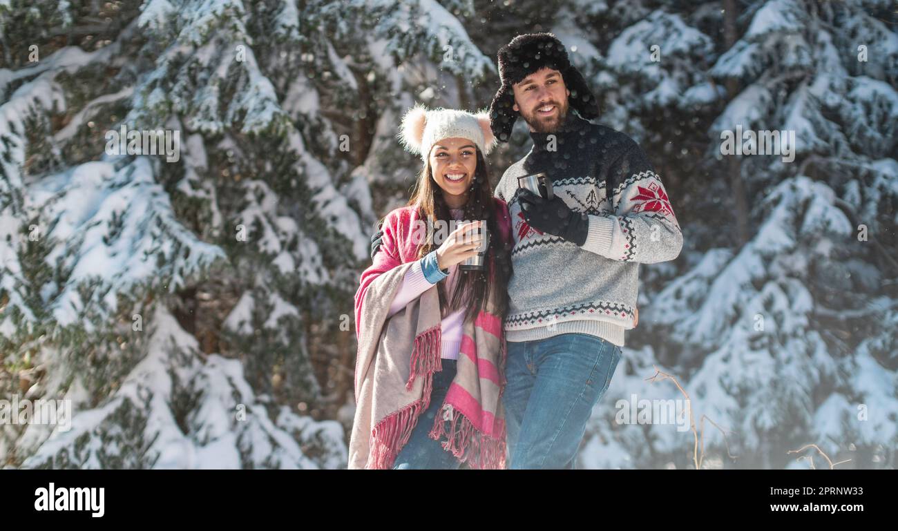 Coppia sorridente che guarda via in caduta di neve Foto Stock