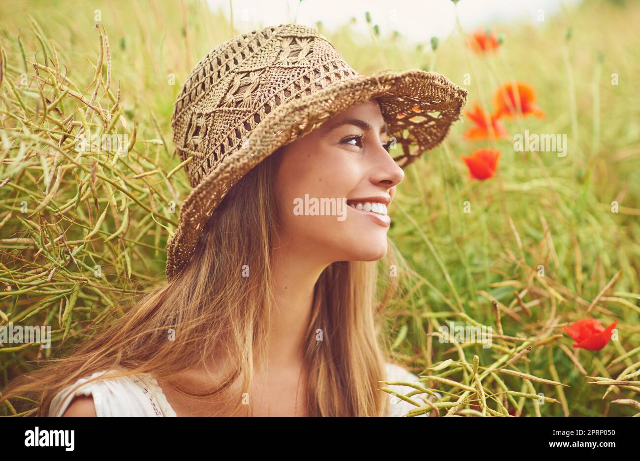 Apprezzando la bellezza di tutto. Una giovane donna seduta in un campo in campagna. Foto Stock