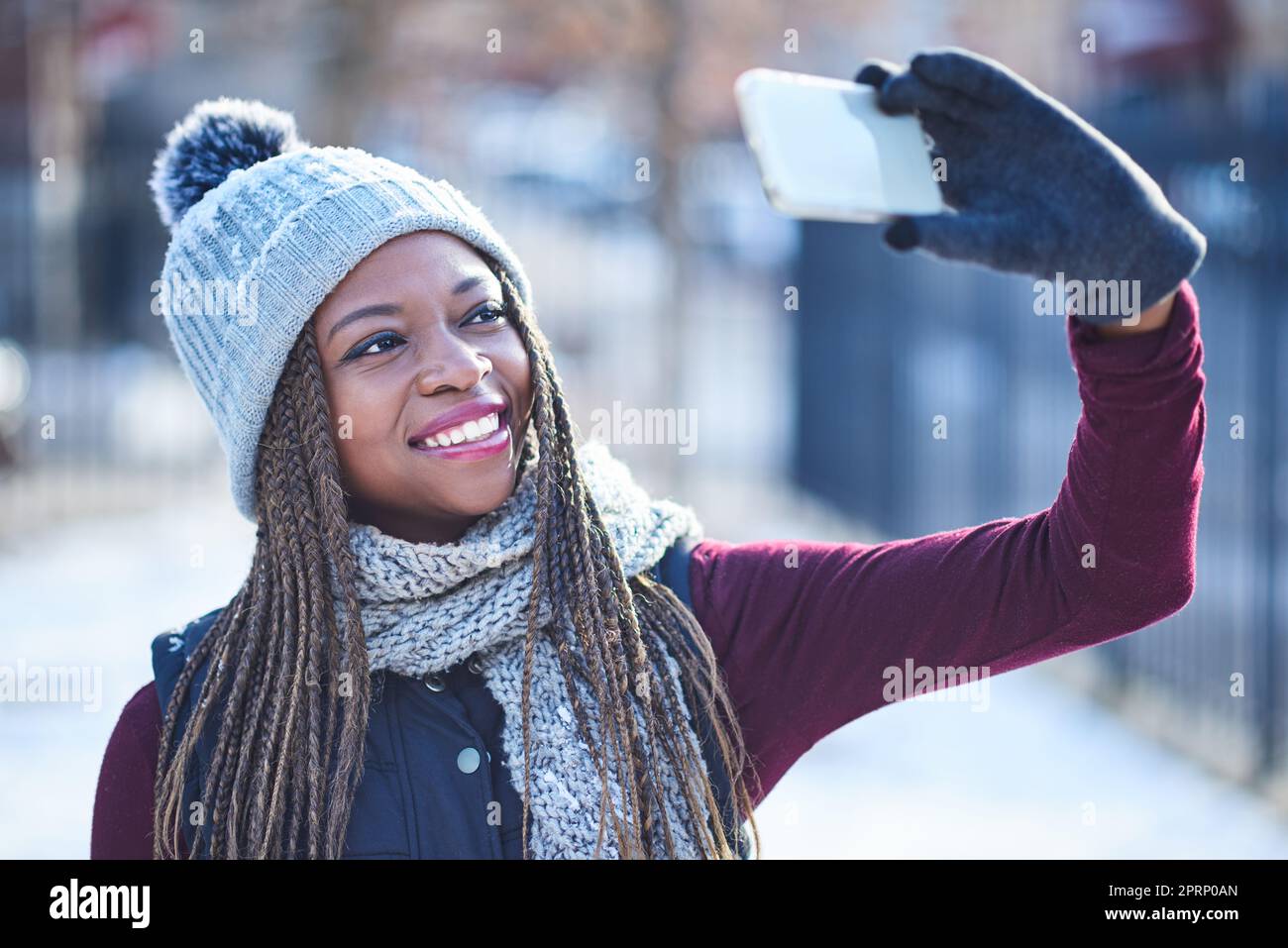 Ecco la neve e i selfie. una bella giovane donna che prende un selfie in una giornata innevata all'aperto Foto Stock