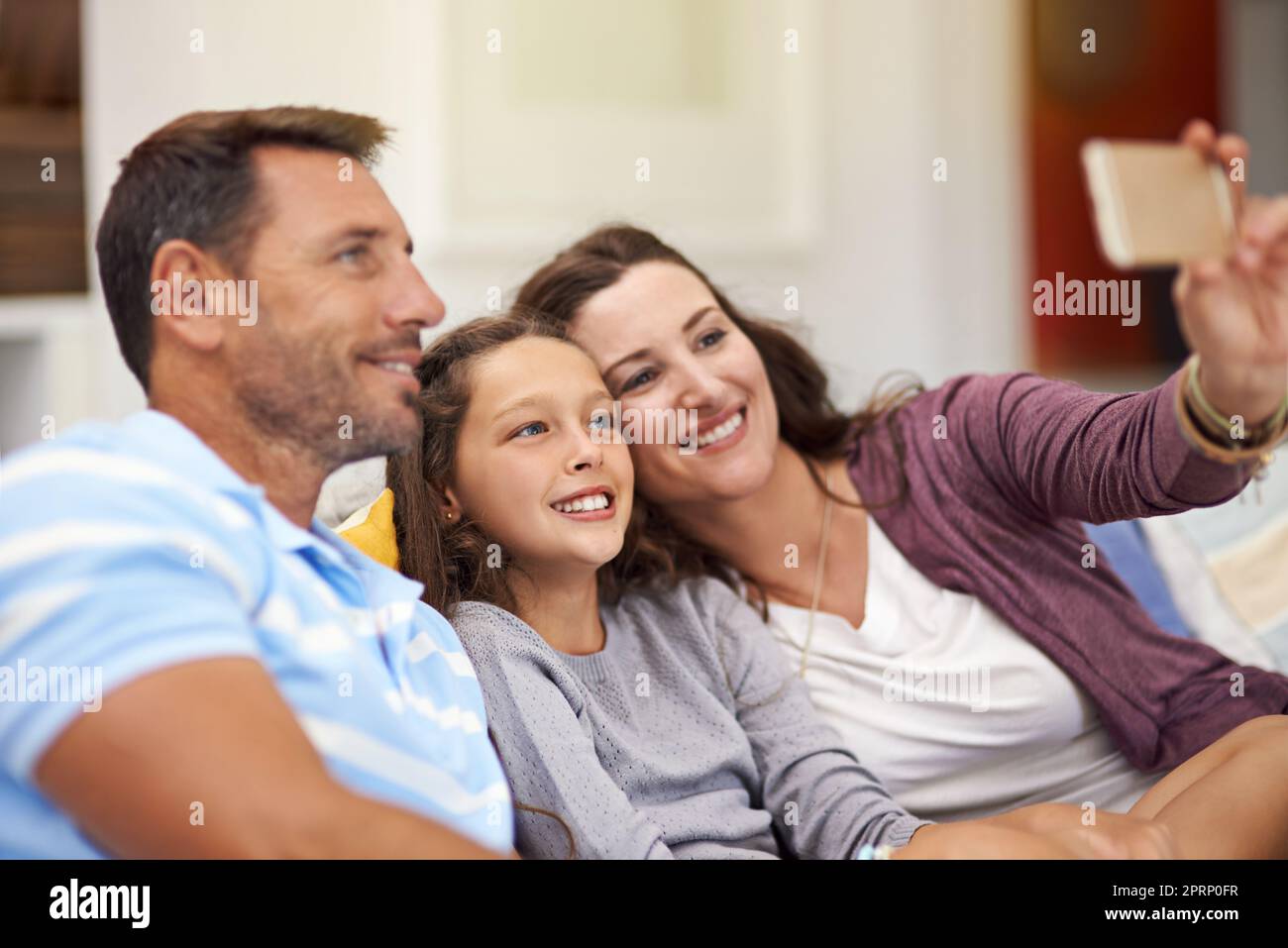 Selfie sorride. Una famiglia seduta sul divano a casa. Foto Stock