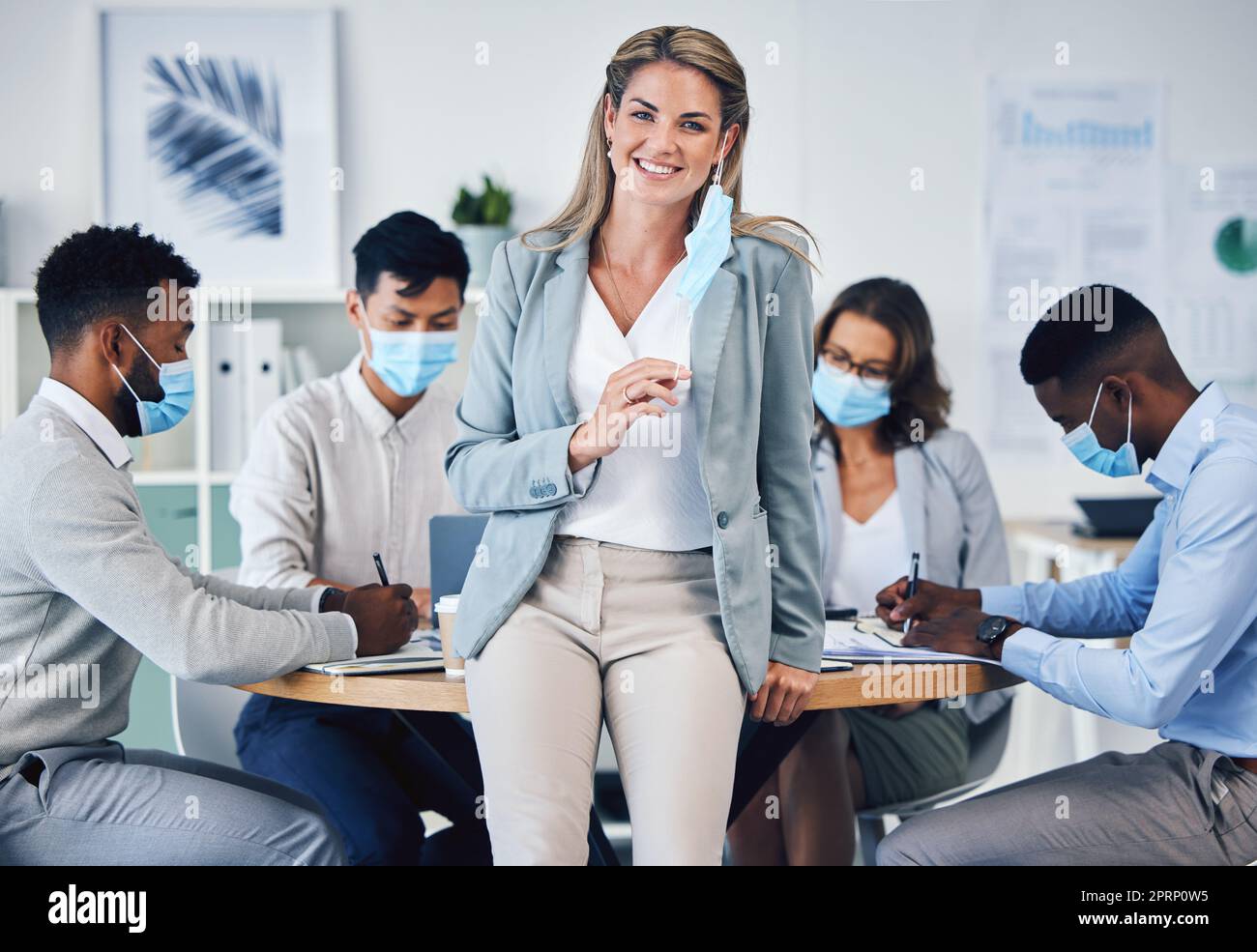 Riunioni, uffici e covid in collaborazione di team tra uomini d'affari e leader Woman nella pianificazione aziendale. Ritratto di una manager donna felice di rimuovere una maschera di coronavirus alla fine di una pandemia. Foto Stock