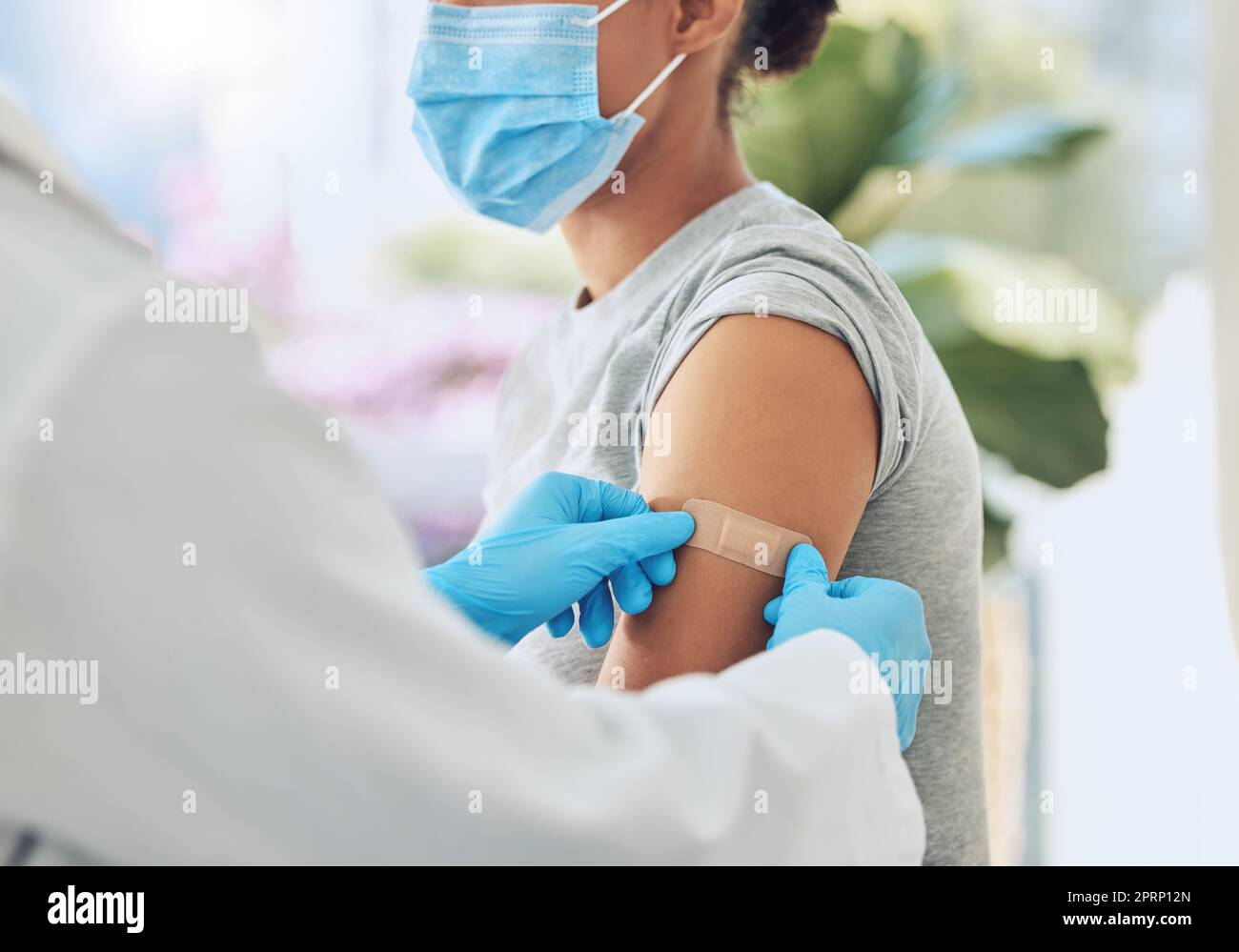 Vaccino contro la COVID con medico o infermiere sanitario mani con gesso sul braccio dopo l'iniezione del farmaco. Trattamento del paziente o assistenza infermieristica per malattia, malattia o influenza sul lavoro in ospedale o clinica. Foto Stock