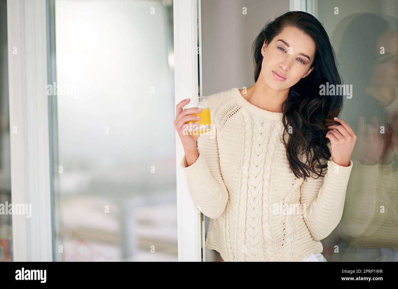 Questo sarà un fine settimana freddo. Ritratto della giovane donna che beve un bicchiere di succo a casa. Foto Stock