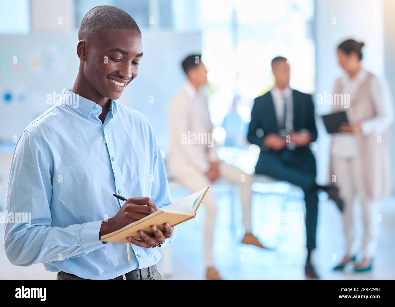 Assistente che scrive appunti in un quaderno per un team di dirigenti ed è soddisfatto di una mentalità, di una visione e di una missione positive. Uomo d'affari afroamericano che usa un diario o un diario per il suo programma Foto Stock