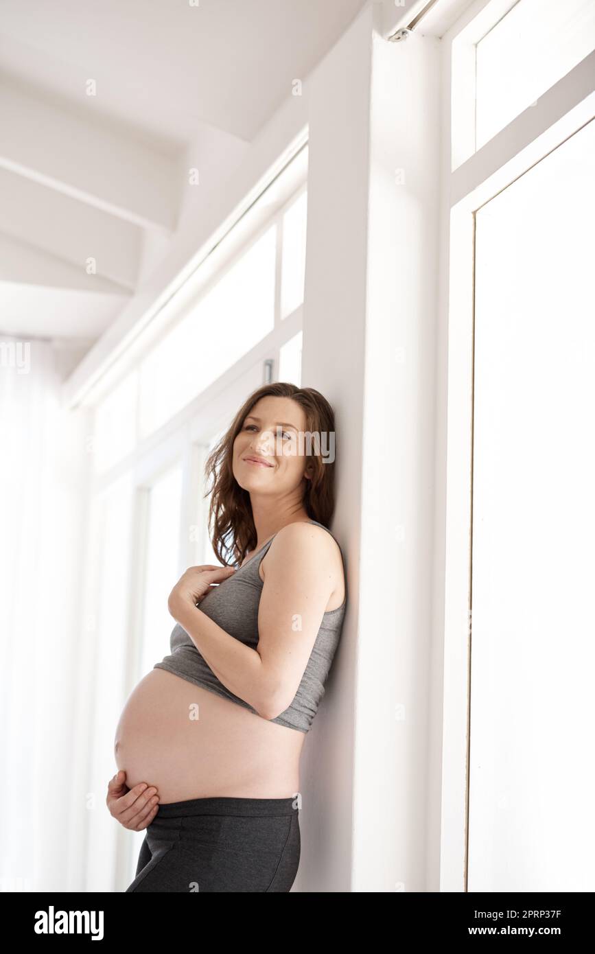 Prendendosi cura del suo bambino prima del relativo sopportato. Una giovane donna incinta in piedi nella sua sede. Foto Stock