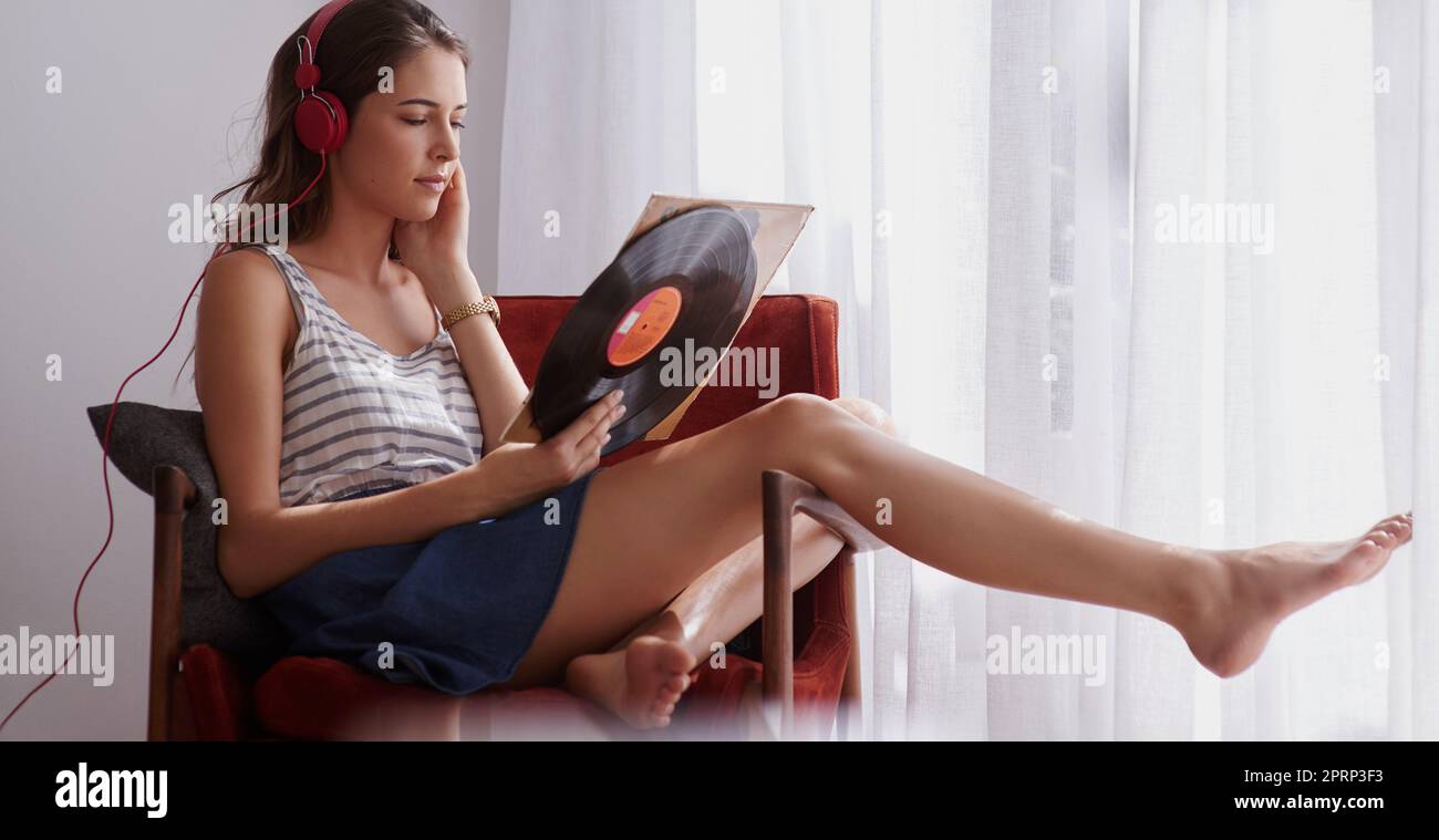 Perdersi nei testi. Una giovane donna che ascolta la musica mentre si rilassa a casa. Foto Stock